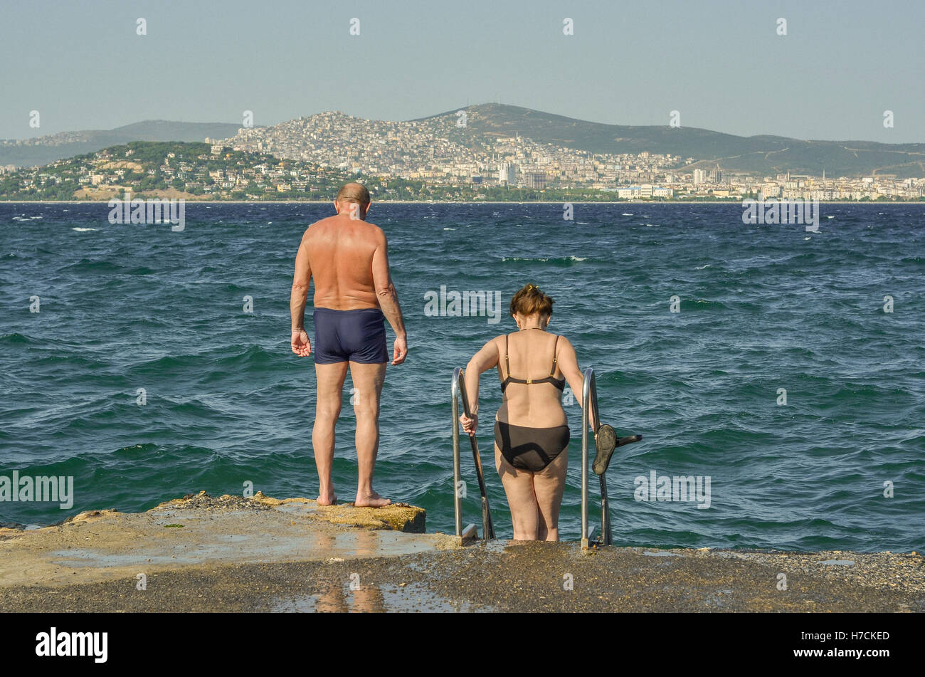 Una coppia di mezz'età si prepara a fare una nuotata nel mare di Marmara sulla Büyükada, il più grande dei principi delle isole. In dist Foto Stock