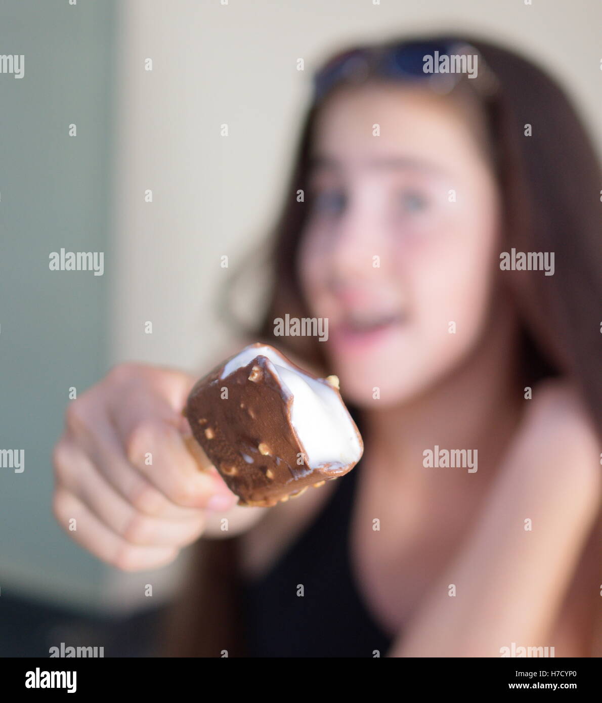 A 13 anni ragazza adolescente celebra l'inizio dell'estate da mangiare un gelato alla vaniglia bar ricoperti di cioccolato e almo Foto Stock