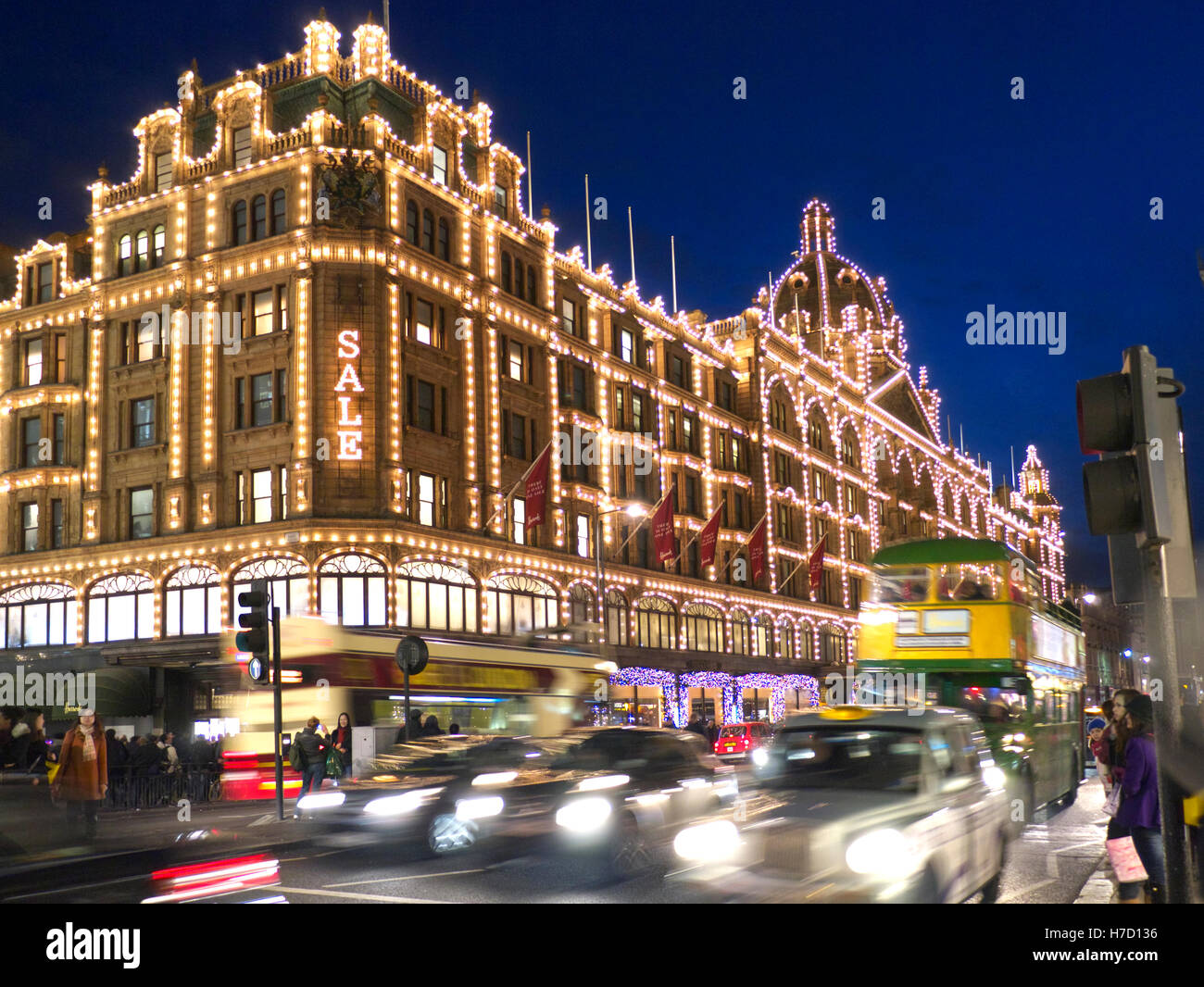 HARRODS VENDITA BLUR LIGHTS ULEZ Harrods grande magazzino di notte con luce 'Sale' segno Shoppers Harrods tour bus e taxi Knightsbridge Londra SW1 Foto Stock