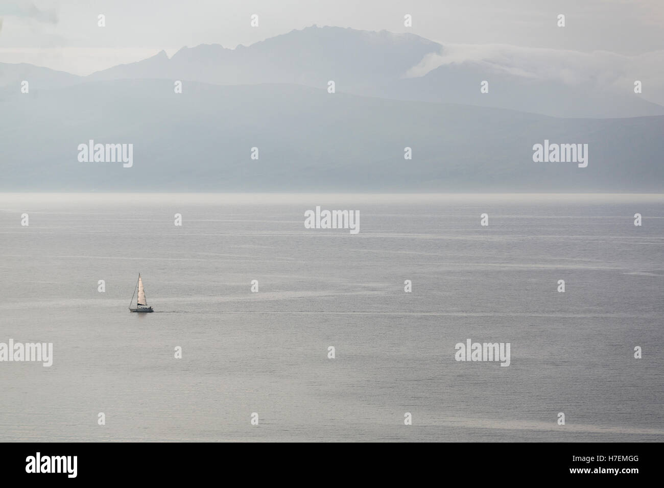 Vista di lone in barca a vela in mare passando l'isola scozzese Isle of Arran in Argyll & Bute, Scozia modello di rilascio: No. Proprietà di rilascio: No. Foto Stock