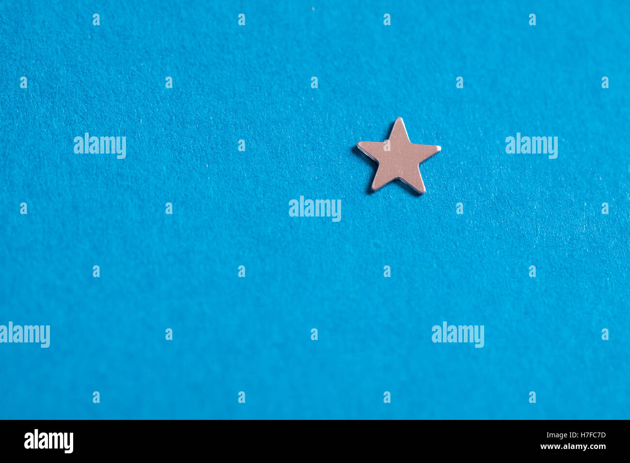 Little Silver star lucido su sfondo blu. Foto Stock