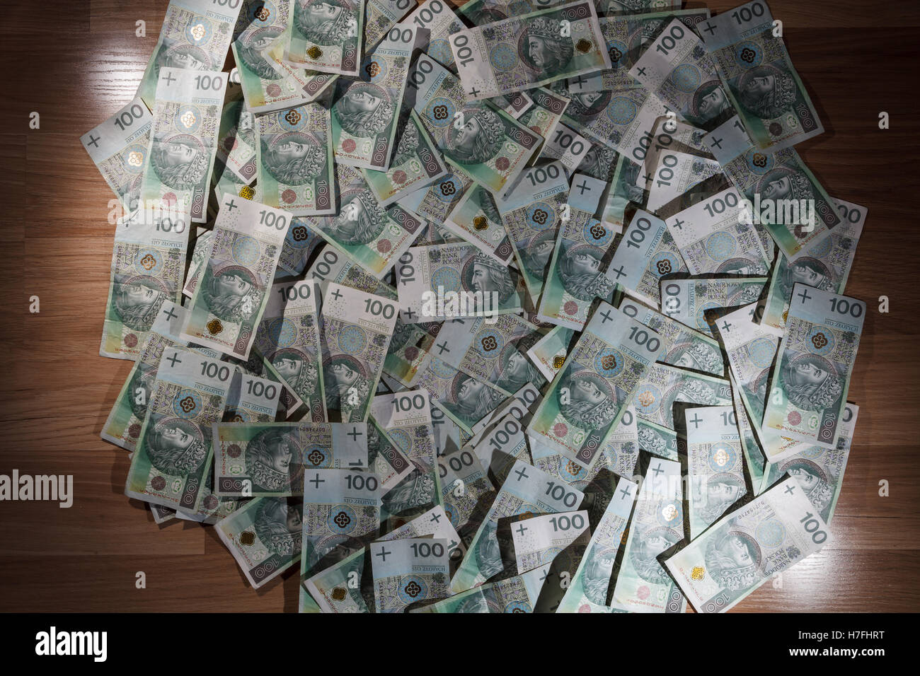 Sfondo di denaro fatte di un centinaio di zloty polacco (PLN) fatture con pavimento in legno, luce laterale e vignette Foto Stock