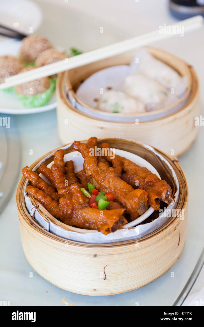 Pollo brasato piedi dim sum in bambù sistema di cottura a vapore è un piatto popolare in cantonese ristoranti di Hong Kong. Foto Stock