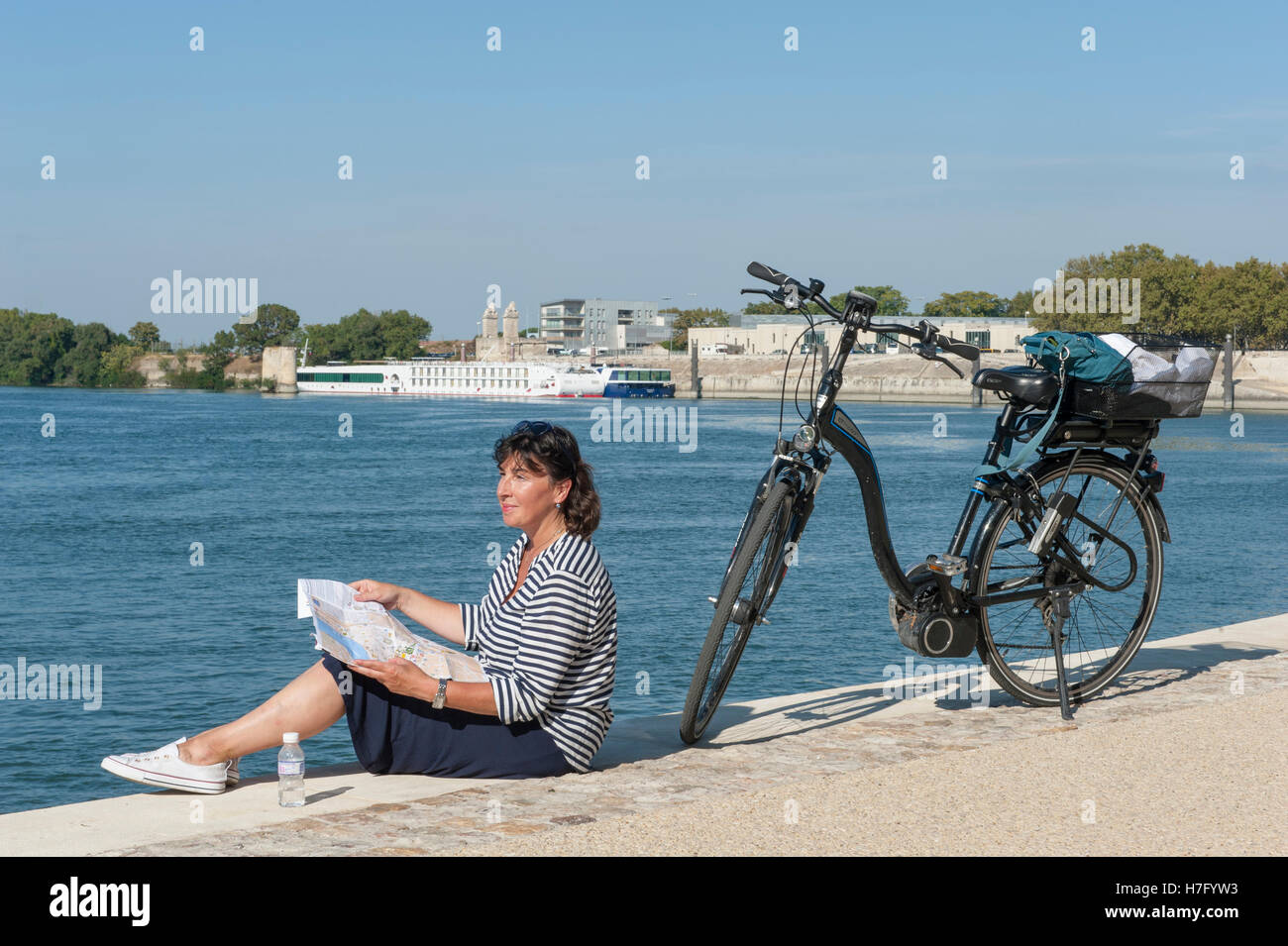 Ciclista femmina (Claudia Albrecht) in appoggio sulle rive del fiume Rodano in Arles, Provenza, Francia Foto Stock