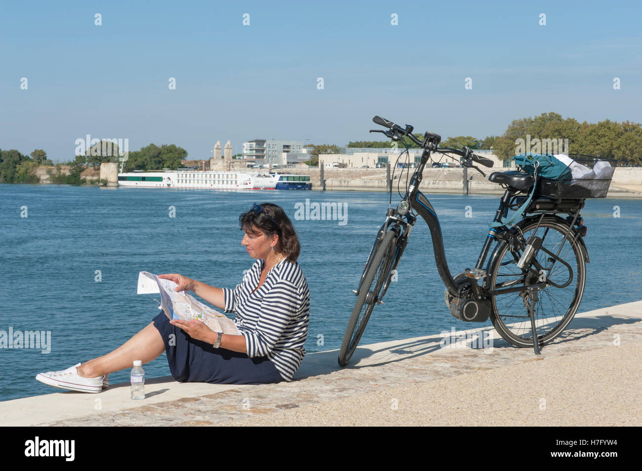 Ciclista femmina (Claudia Albrecht) in appoggio sulle rive del fiume Rodano in Arles, Provenza, Francia Foto Stock