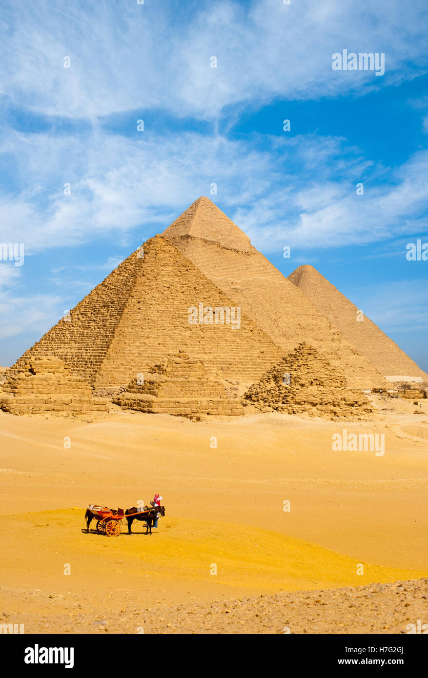 Un gruppo di turisti smontare il loro cavallo carrello per visualizzare tutte le piramidi egiziane insieme su un wispy nuvoloso giorno del Cairo in Egitto Foto Stock