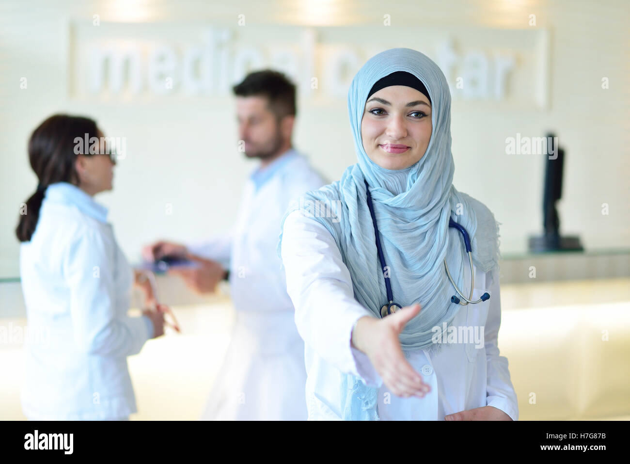 Giovani sorridenti femmina medico musulmano dando la mano per lo handshaking Foto Stock