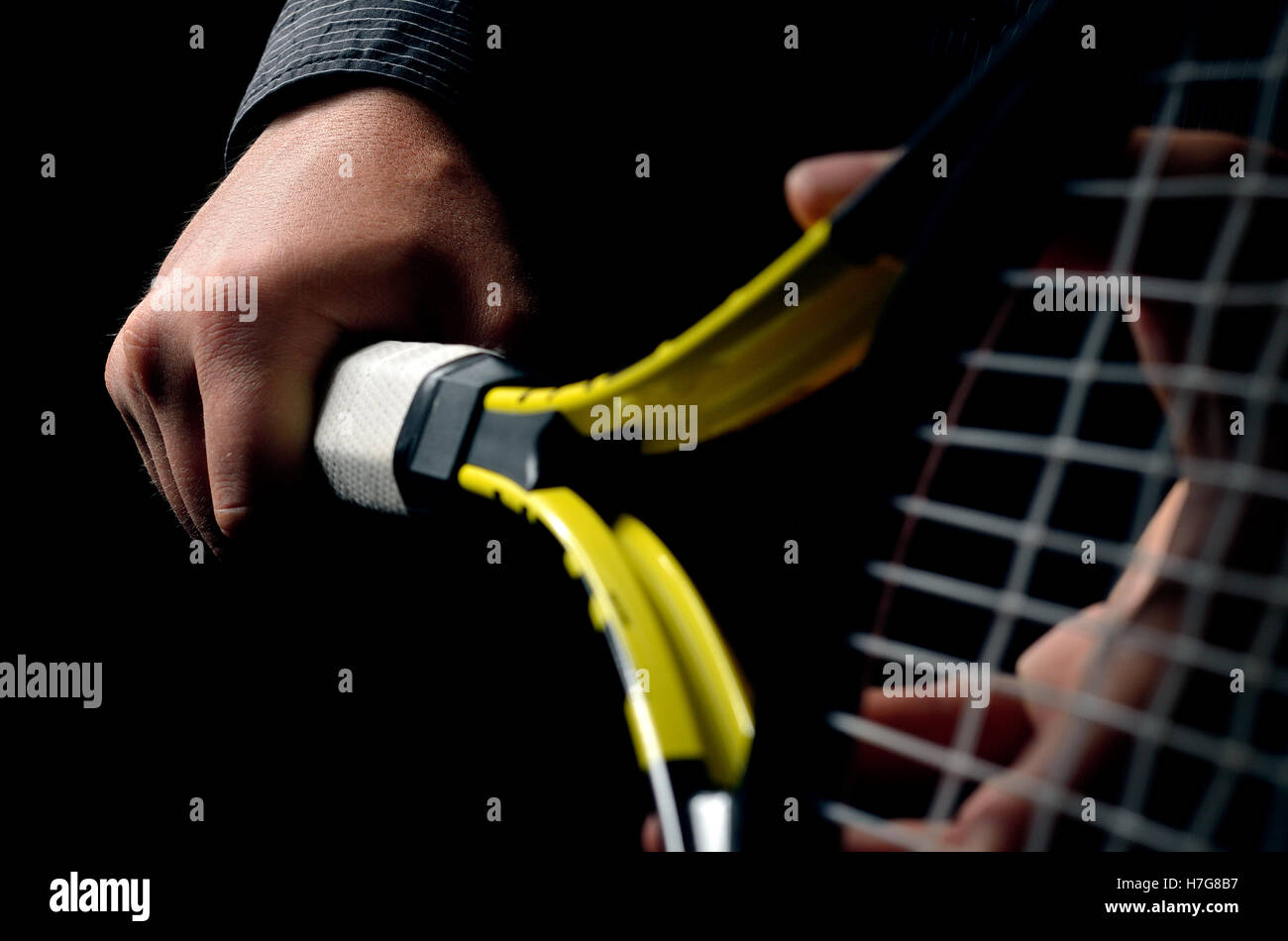 Sulla mano di presa oscillante e una racchetta da tennis. Isolato su sfondo nero. Foto Stock