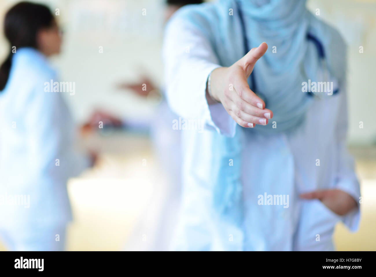 Giovani sorridenti femmina medico musulmano dando la mano per lo handshaking Foto Stock