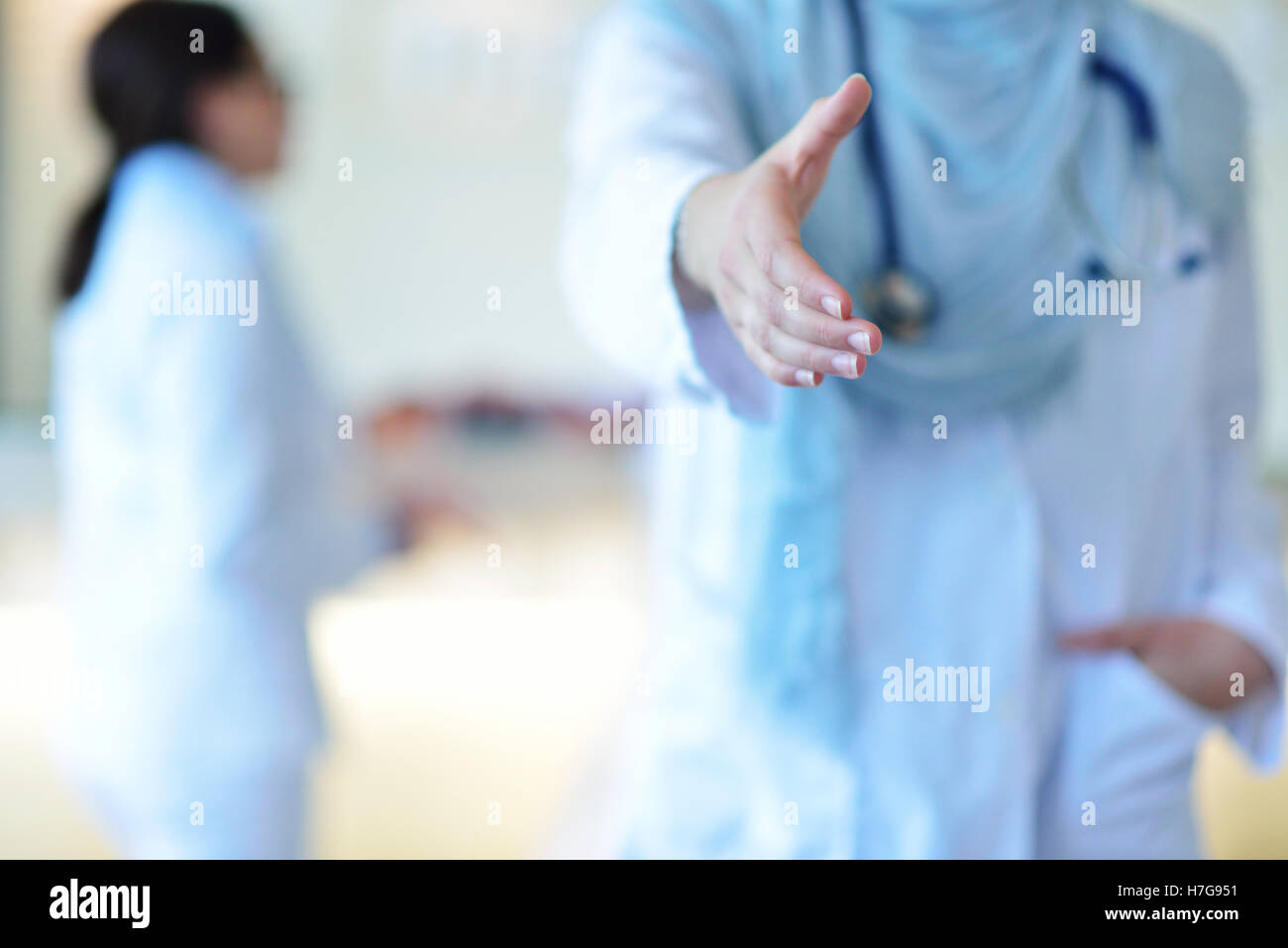 Giovani sorridenti femmina medico musulmano dando la mano per lo handshaking Foto Stock