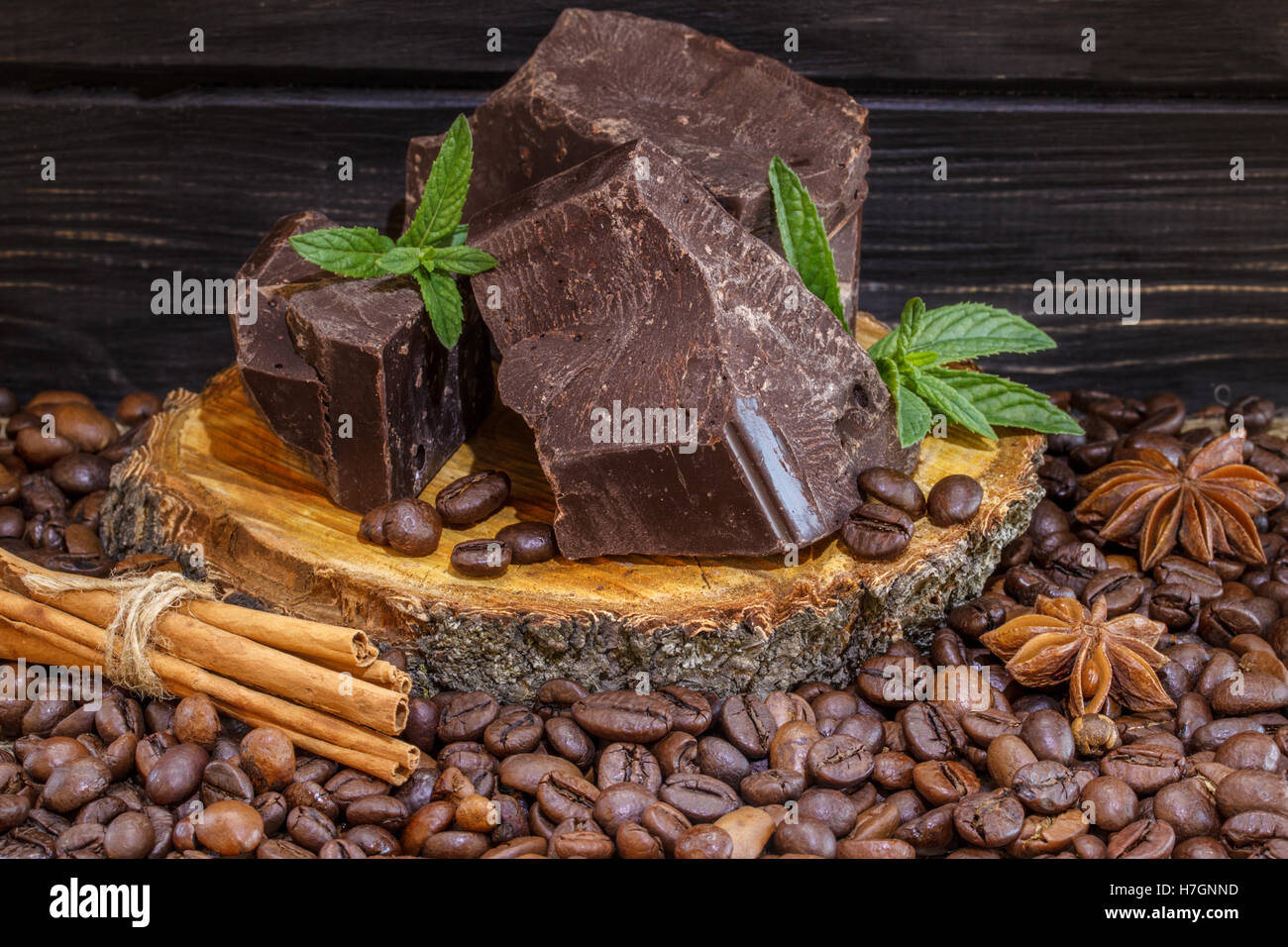 Cioccolato fondente al caffè in grani, cannella e anice stellato su una tavola di legno Foto Stock