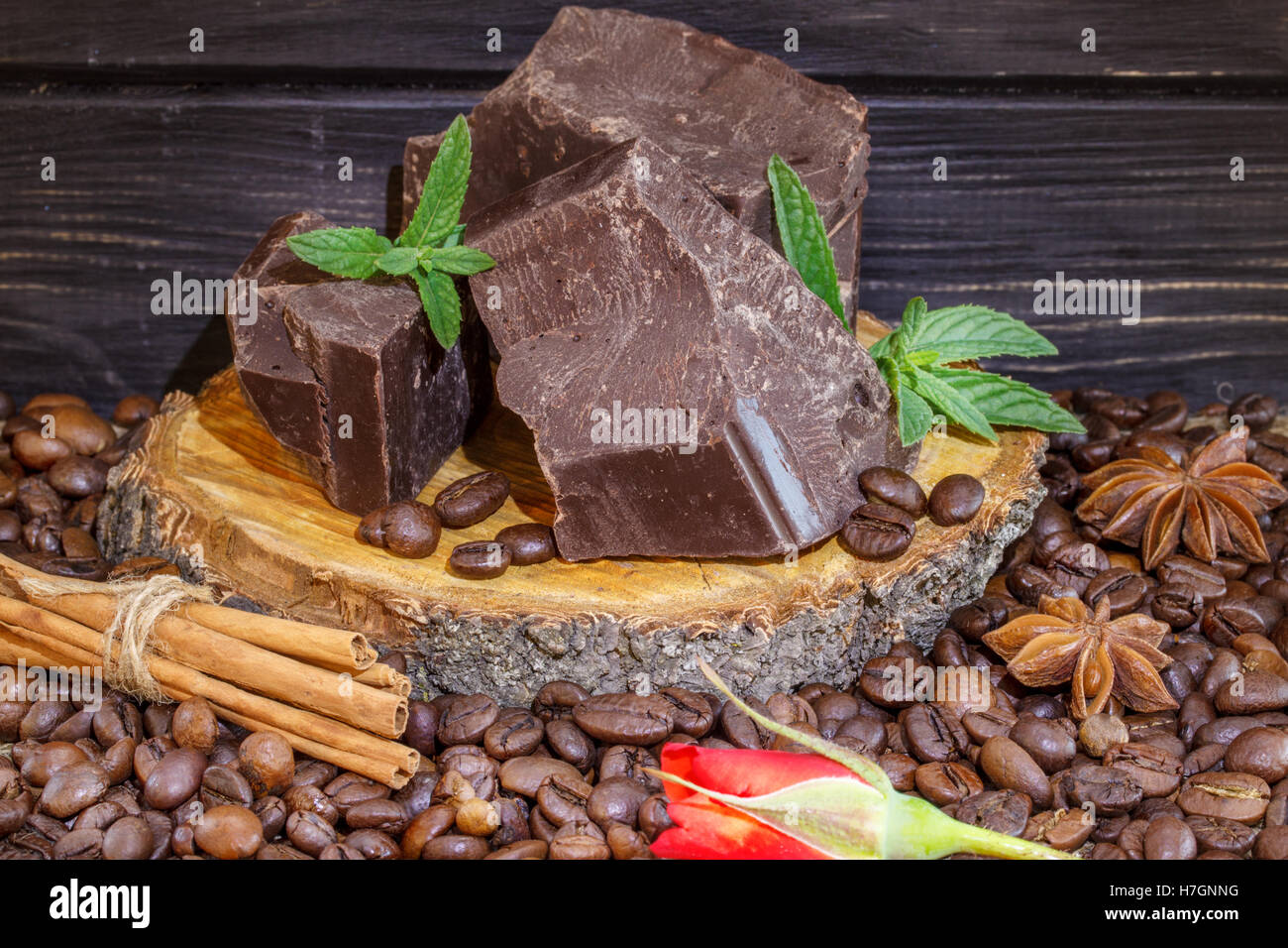 Cioccolato fondente al caffè in grani, cannella e anice stellato su una tavola di legno Foto Stock