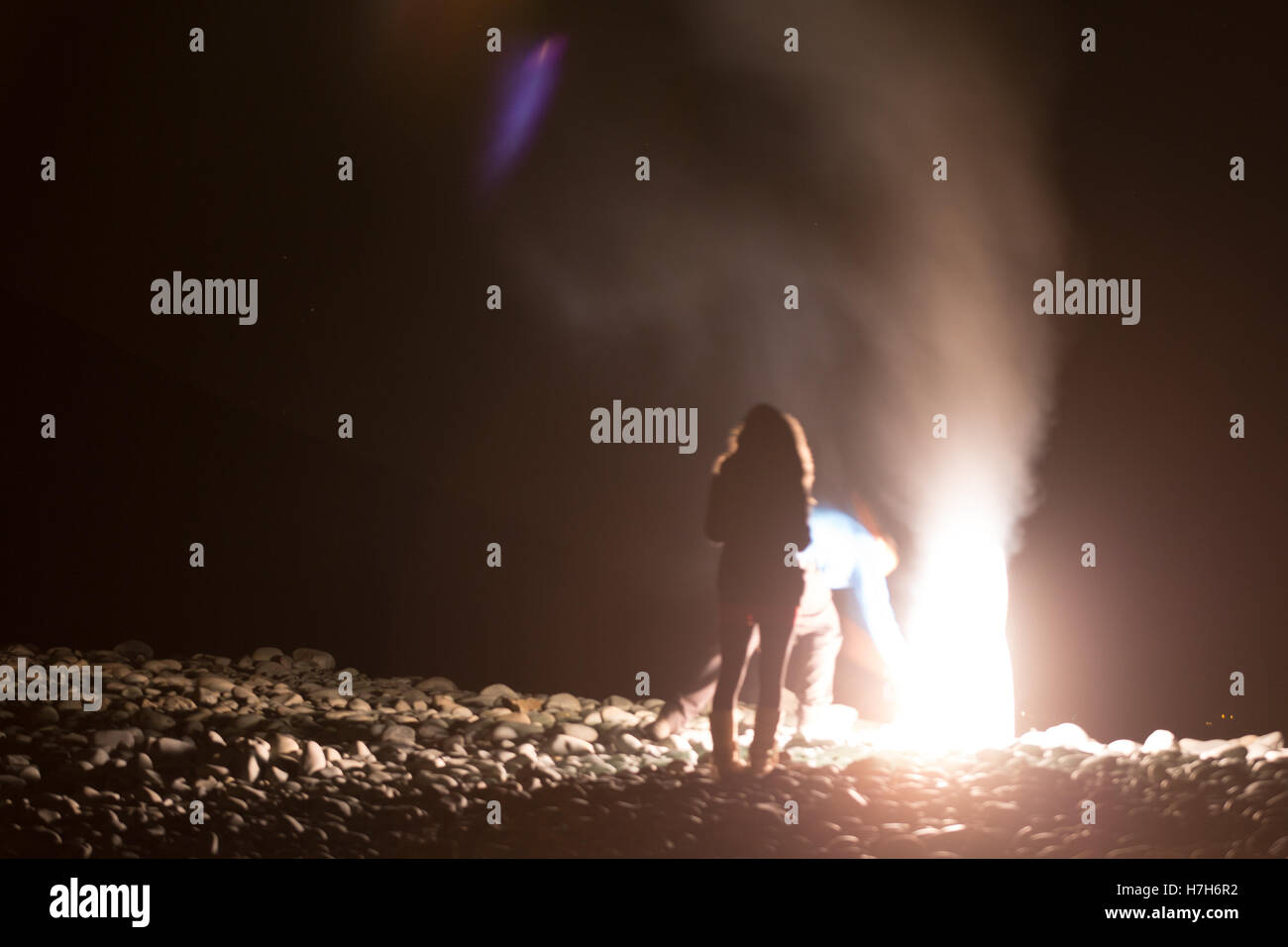 Un uomo di tentativi di ri-acceso il suo fuoco d'artificio quasi con conseguenze fatali come egli si appoggia sopra, set off manca solo il suo volto. Foto Stock