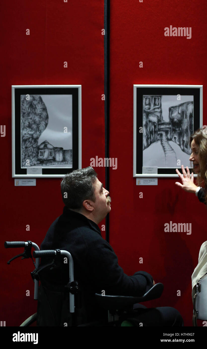 Francoforte, Germania. 5 Novembre, 2016. Artista rumeno Cristinel Melkonian introduce i suoi dipinti di un visitatore a un evento artistico per i Romeni artisti che vivono a Francoforte, durante la Settimana interculturale a Francoforte in Germania, su nov. 5, 2016. La Settimana interculturale si è tenuto qui da ott. 29 nov. 12. © Luo Huanhuan/Xinhua/Alamy Live News Foto Stock