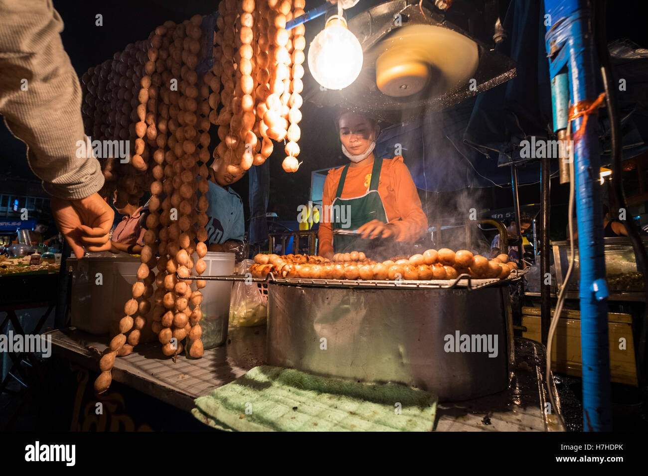 Una donna di vendita di alimenti a Chiang Mai a piedi dal mercato notturno, Thailandia Foto Stock