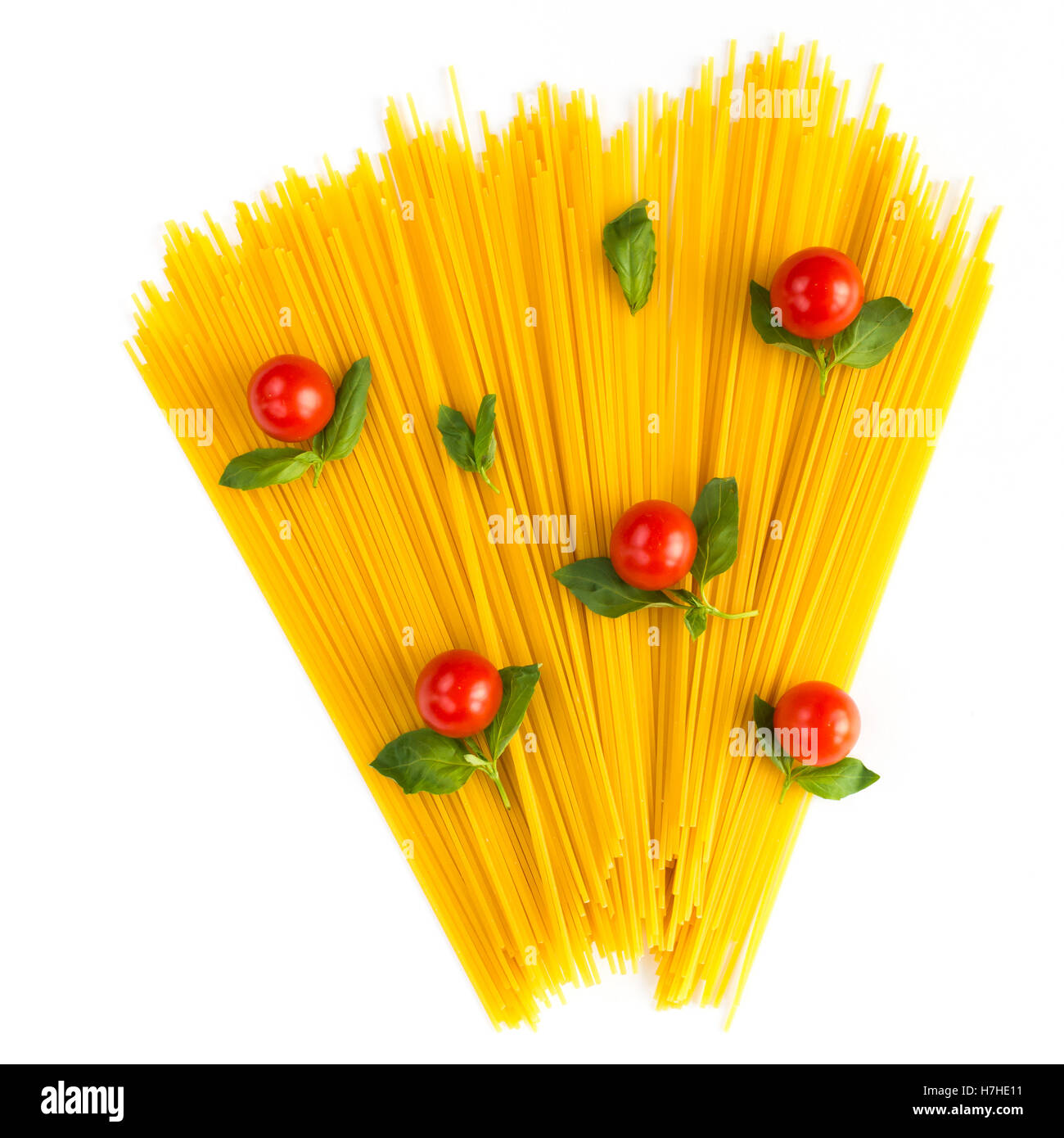 Spaghetti italiani di materie prime con il rosso dei pomodori e basilico fresco di foglie su una lavagna bianca di sfondo, vista dall'alto Foto Stock
