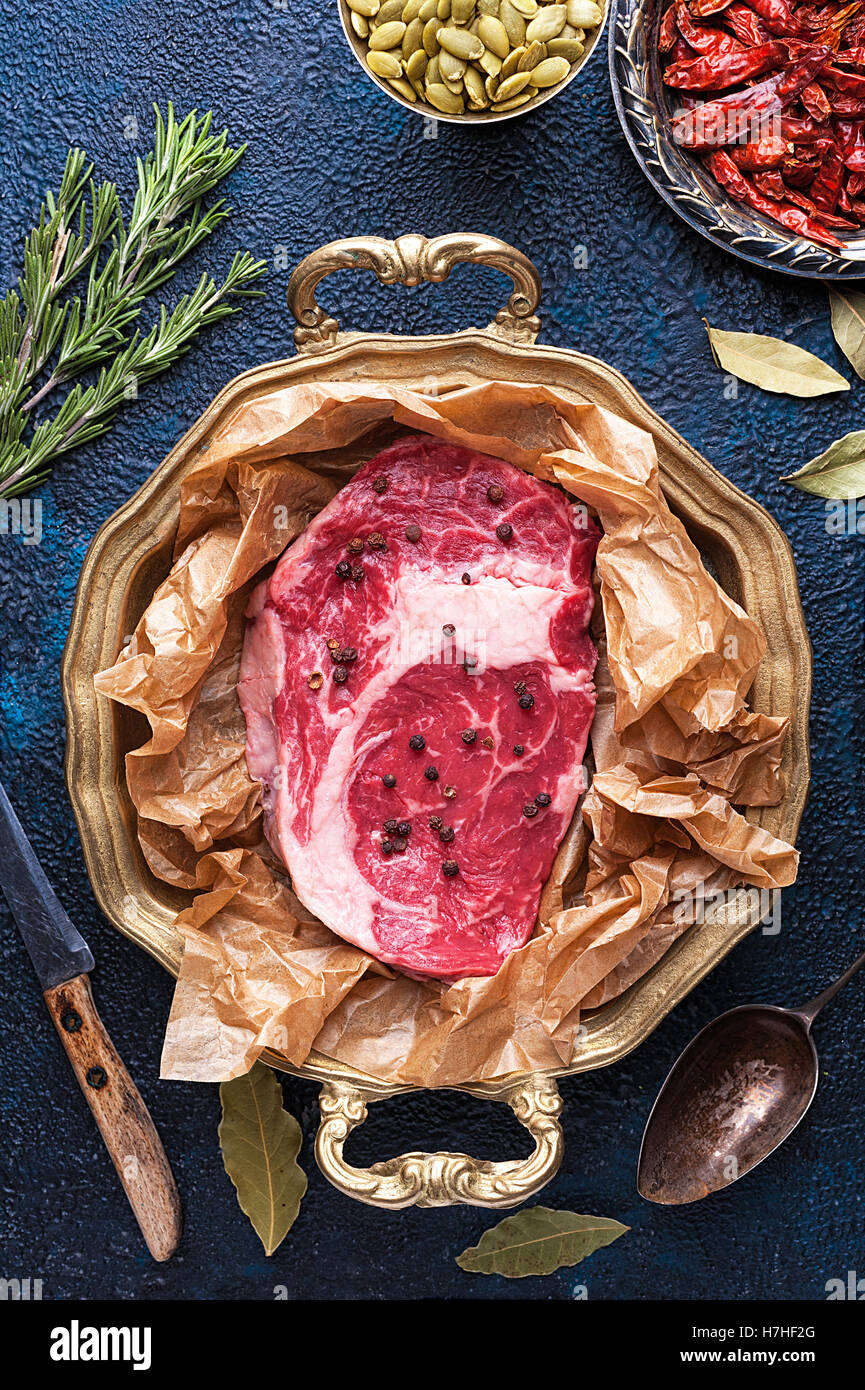 Pezzo di carne di manzo sul vassoio circondato da spezie Foto Stock