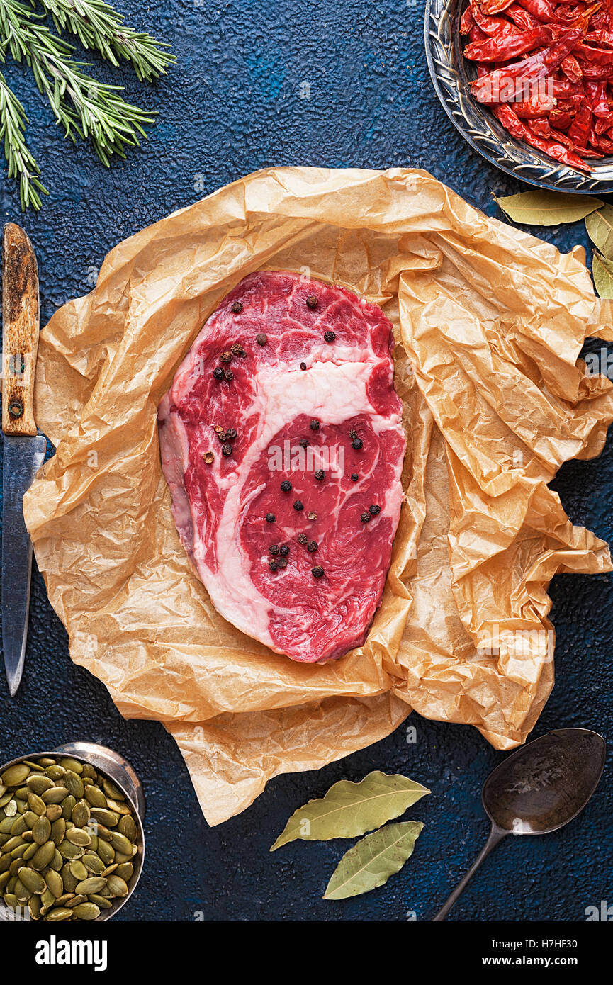 Pezzo di carne di manzo su carta circondato da spezie con spazio di copia Foto Stock