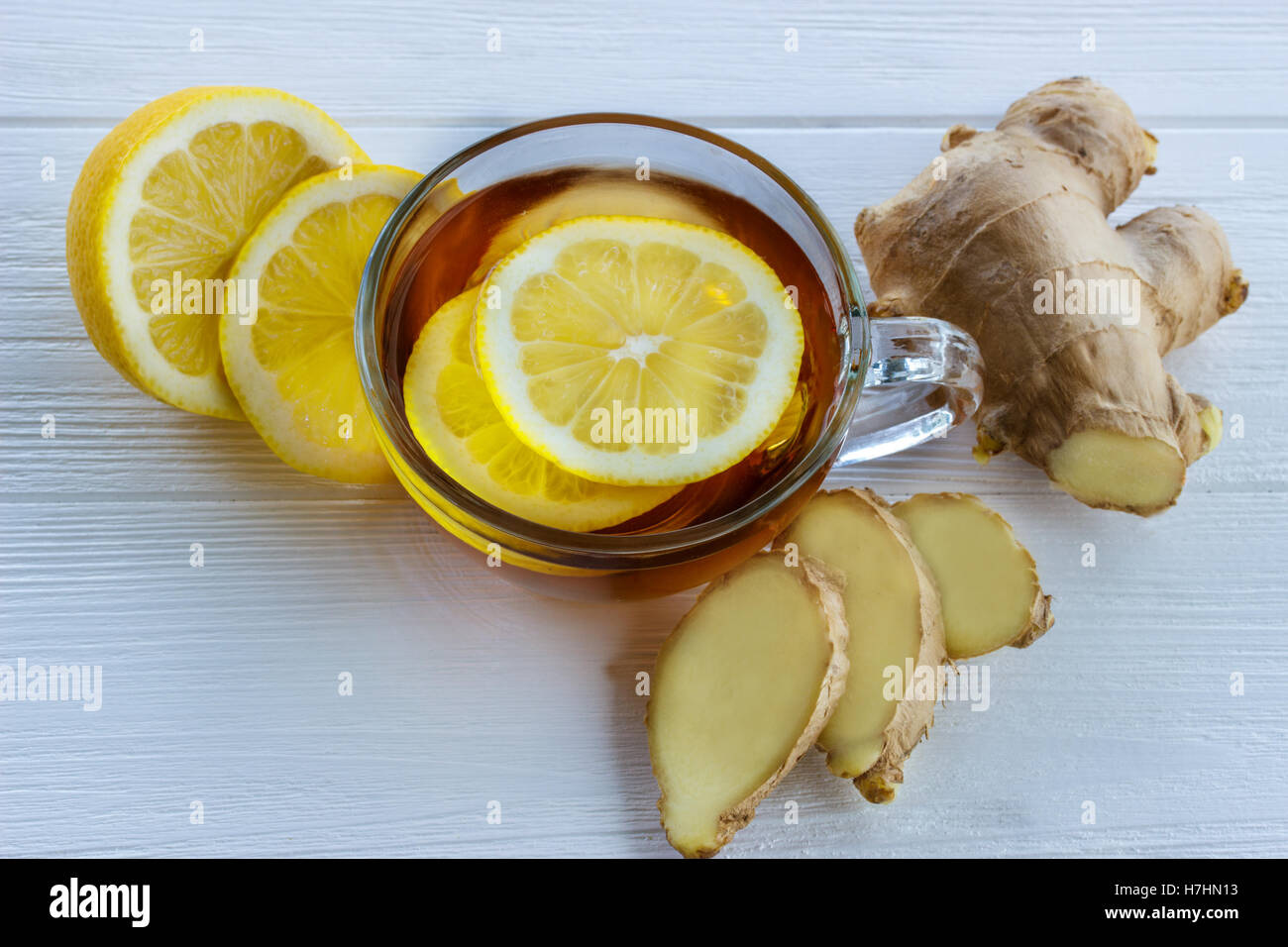 Tazza di tè allo zenzero con limone e zenzero fresco sul tagliere di legno Foto Stock