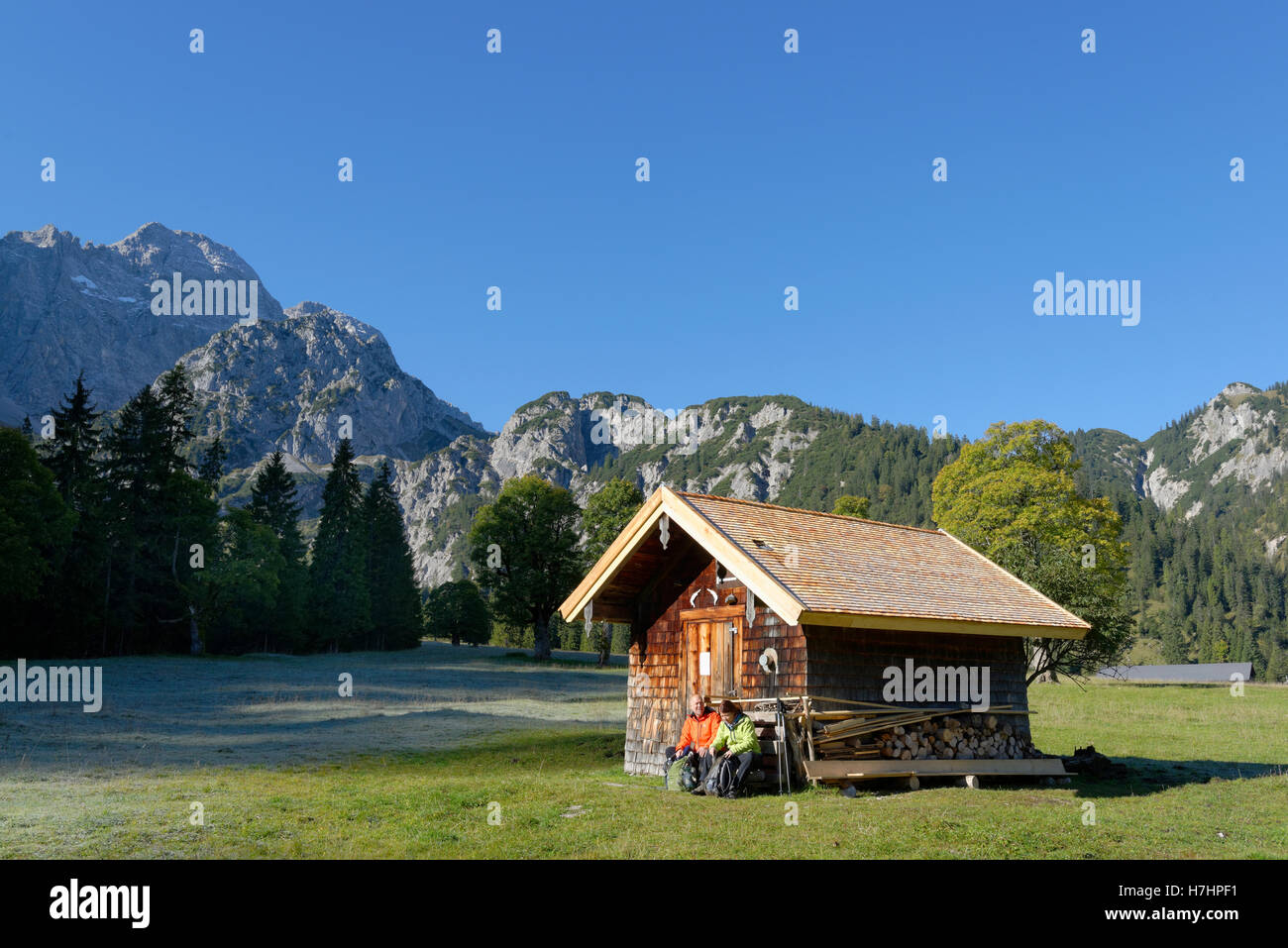 Gli escursionisti in appoggio capanna in legno, snacking, Rohntal a Pürschalm, Eng, Karwendel, Rißtal, Rissbachtal, Tirolo, Austria Foto Stock