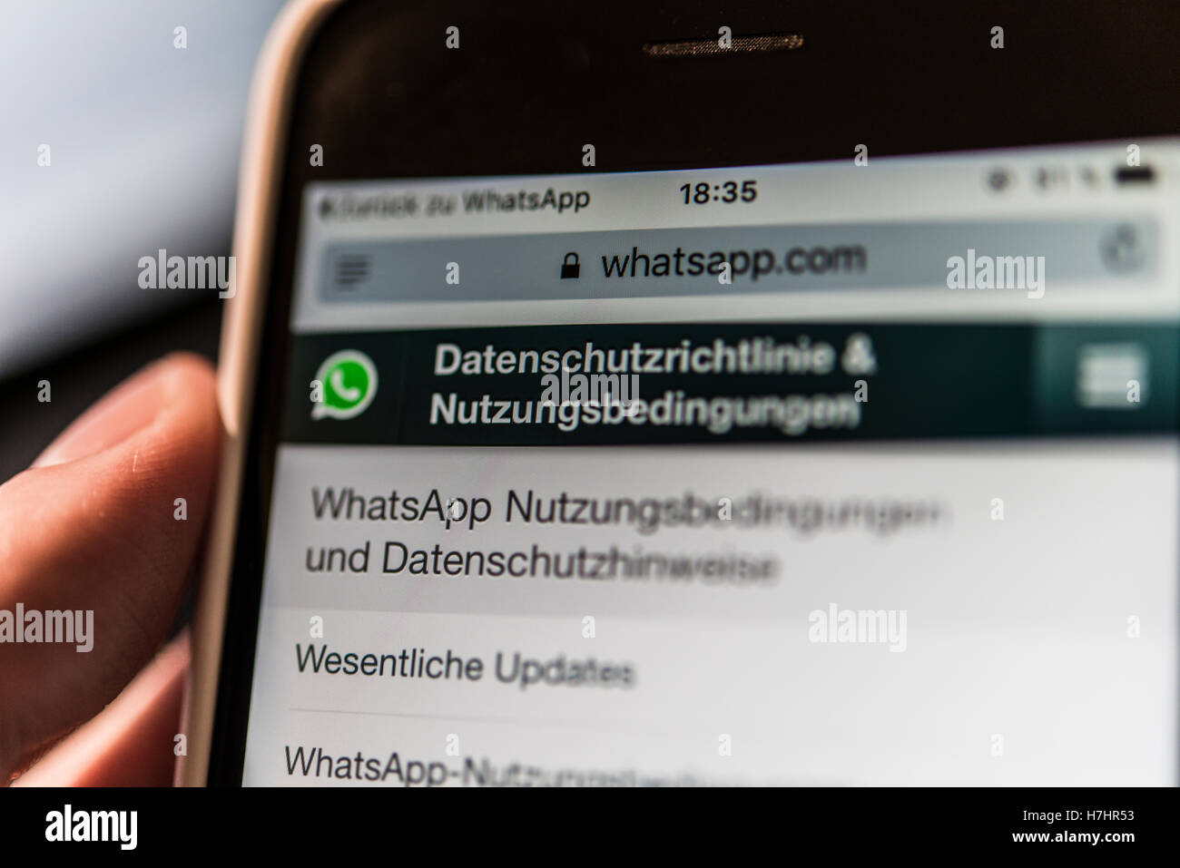 Mano che tiene iPhone visualizza WhatsApp Termini di servizio e informativa sulla privacy Foto Stock