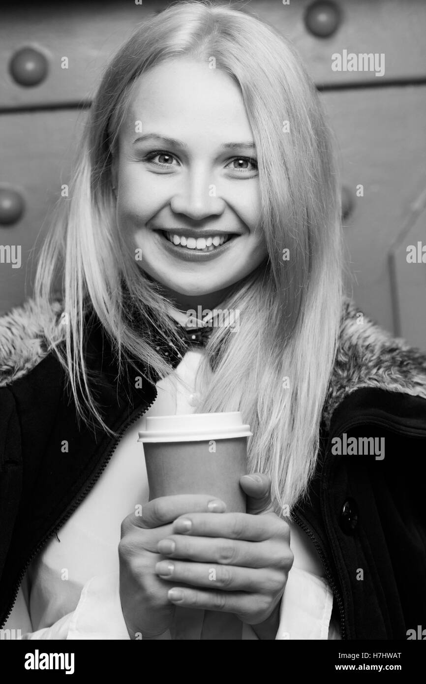 Bella ragazza sorridente tenendo la carta tazza di caffè, nero-bianco foto Foto Stock