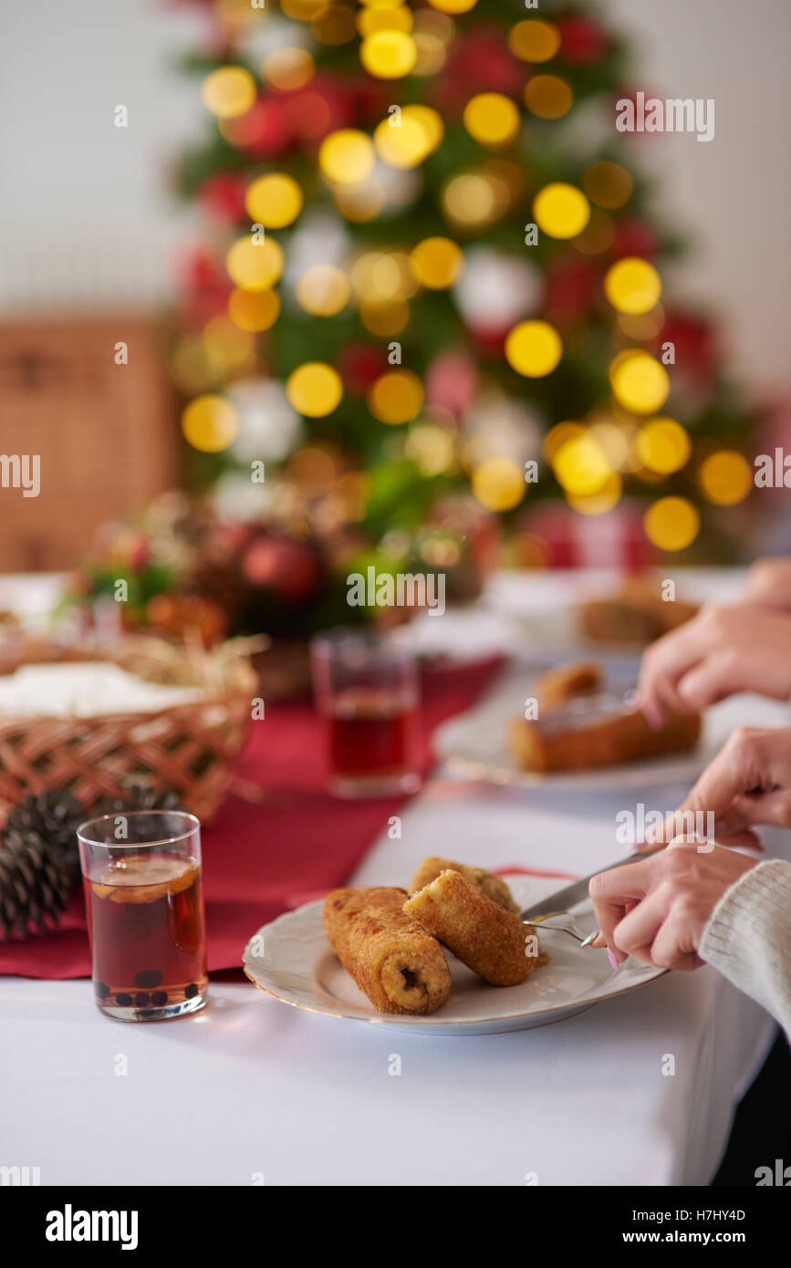 Persone mangiare crocchette di purè di patate durante la vigilia di Natale Foto Stock