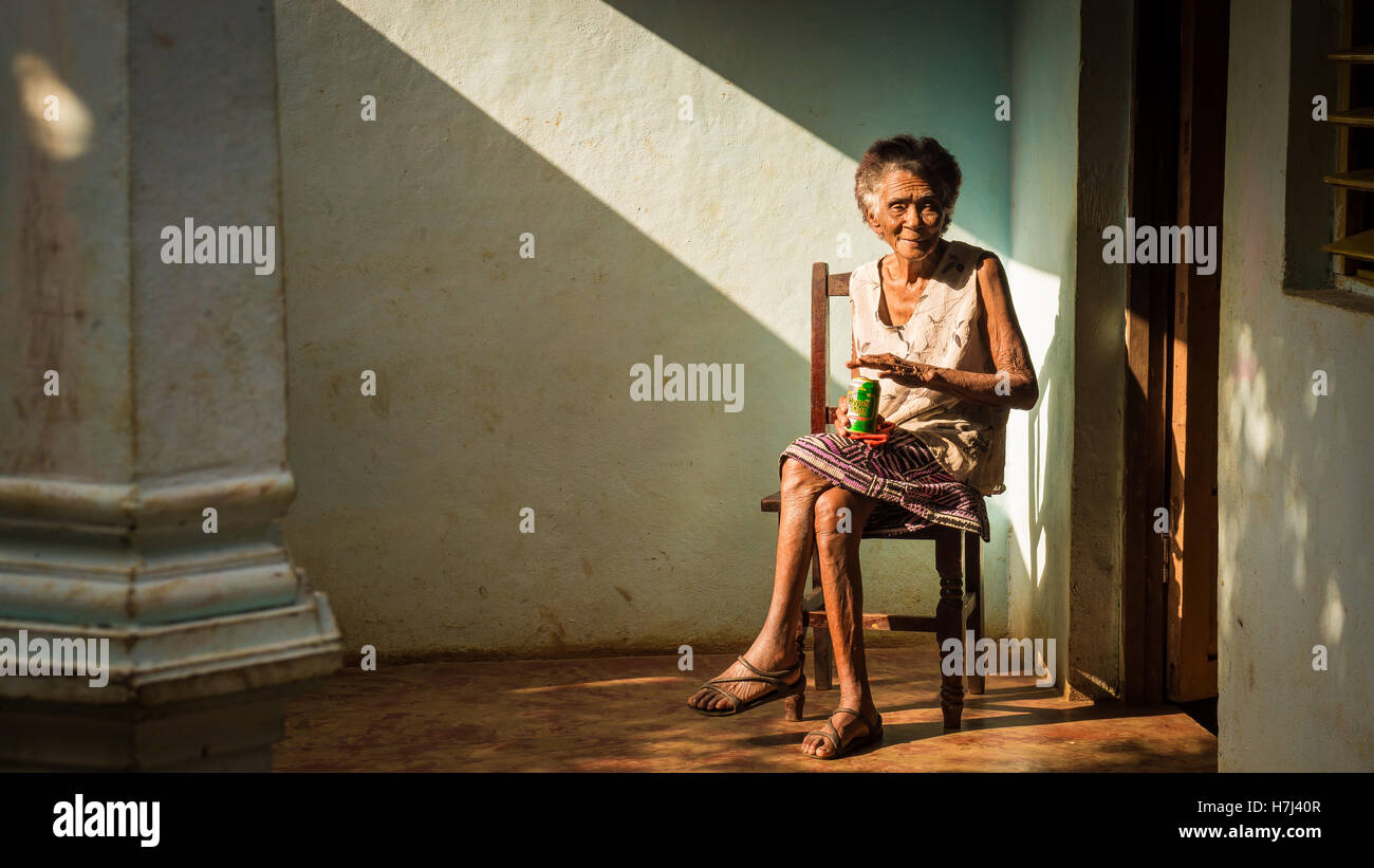 Vecchia donna cubana sulla poltrona gustando una birra Foto Stock