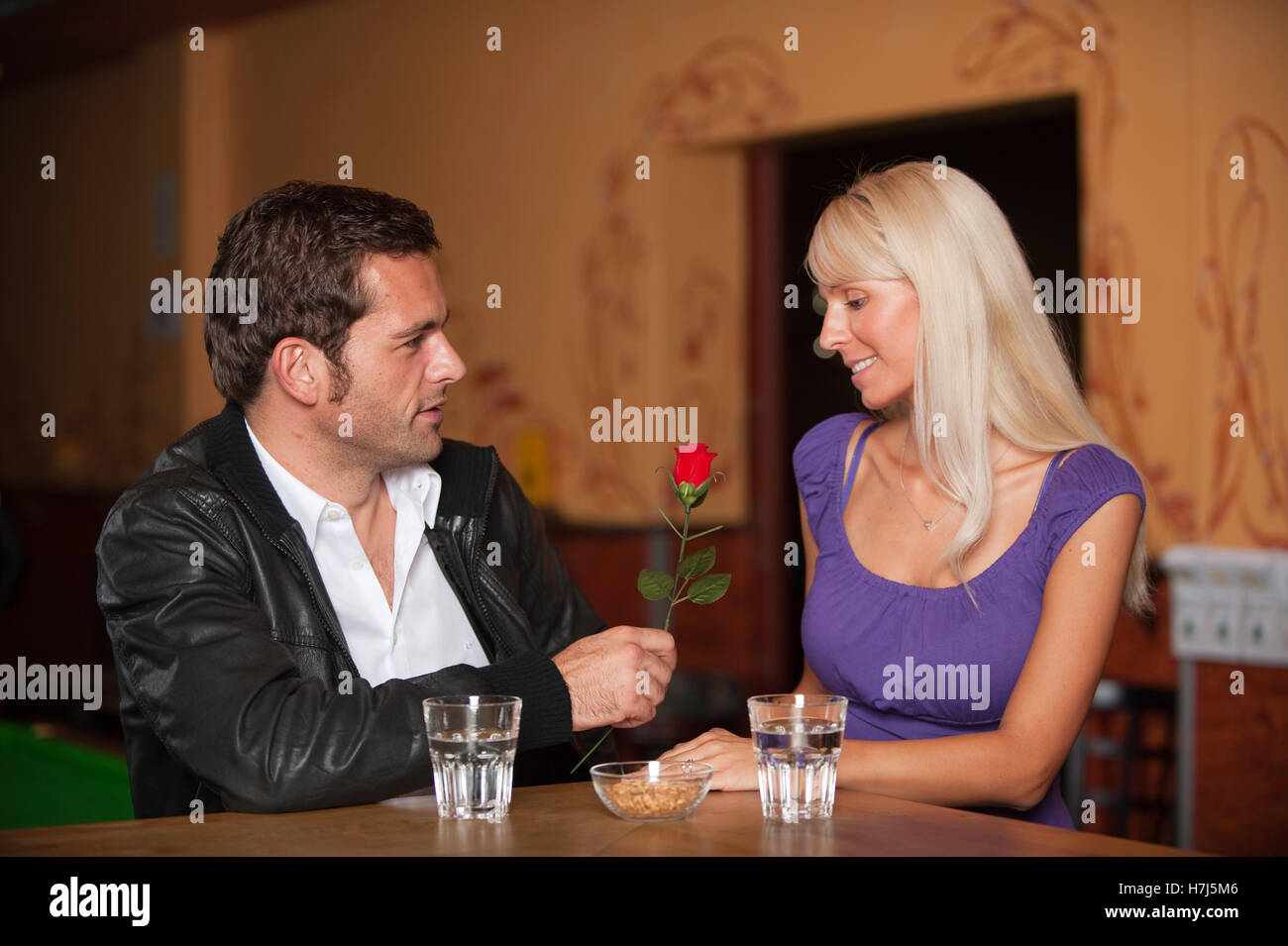 La data, l uomo e la donna con una rosa rossa al bar Foto Stock
