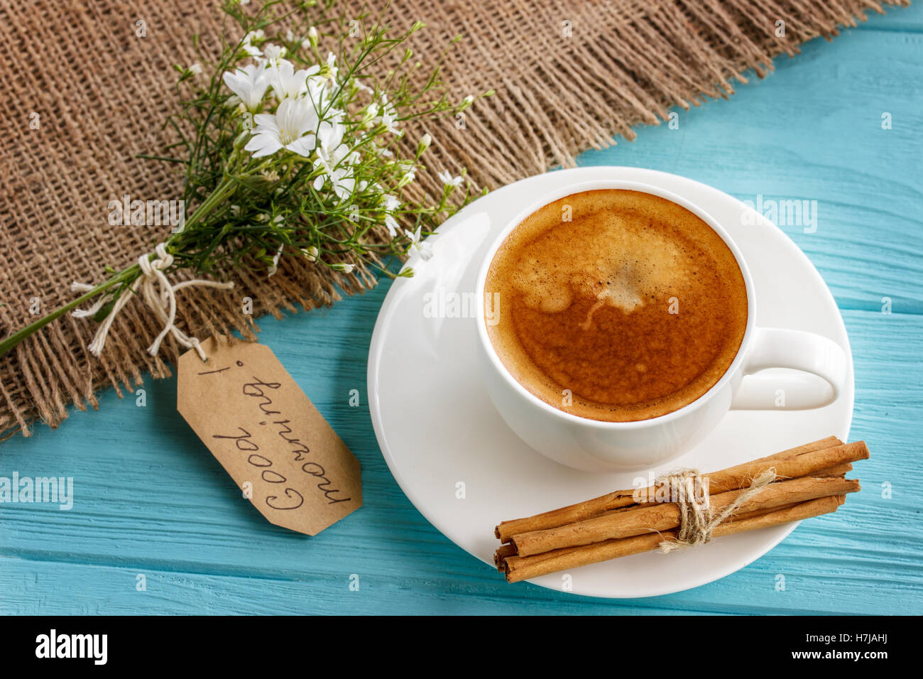 Tazza da caffè con fiori bianchi e le note di buona mattina blu sul tavolo rustico da sopra, prima colazione Foto Stock
