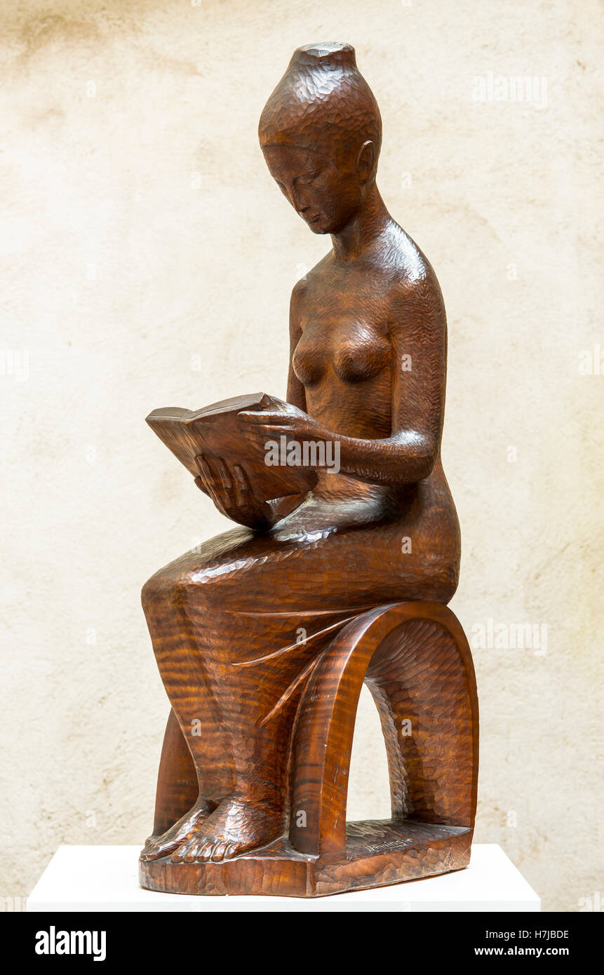 Il lettore, donna che legge un libro, scultura in legno di mogano dello scultore francese Jean Henninge Foto Stock