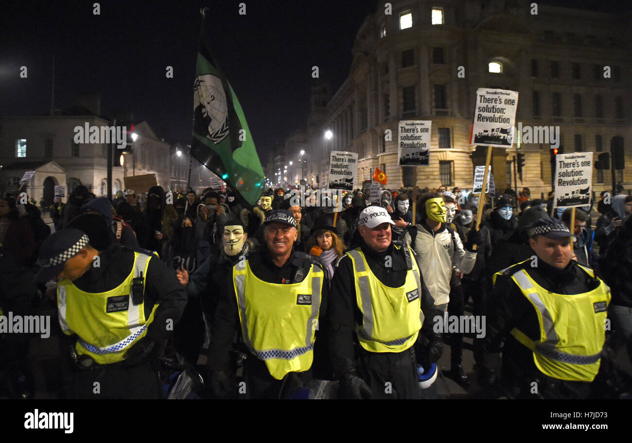 I manifestanti seguire verso il basso della polizia di Whitehall, Londra, durante la maschera di milioni di marzo notte dei falò protesta organizzata dal gruppo attivista anonimo. Foto Stock