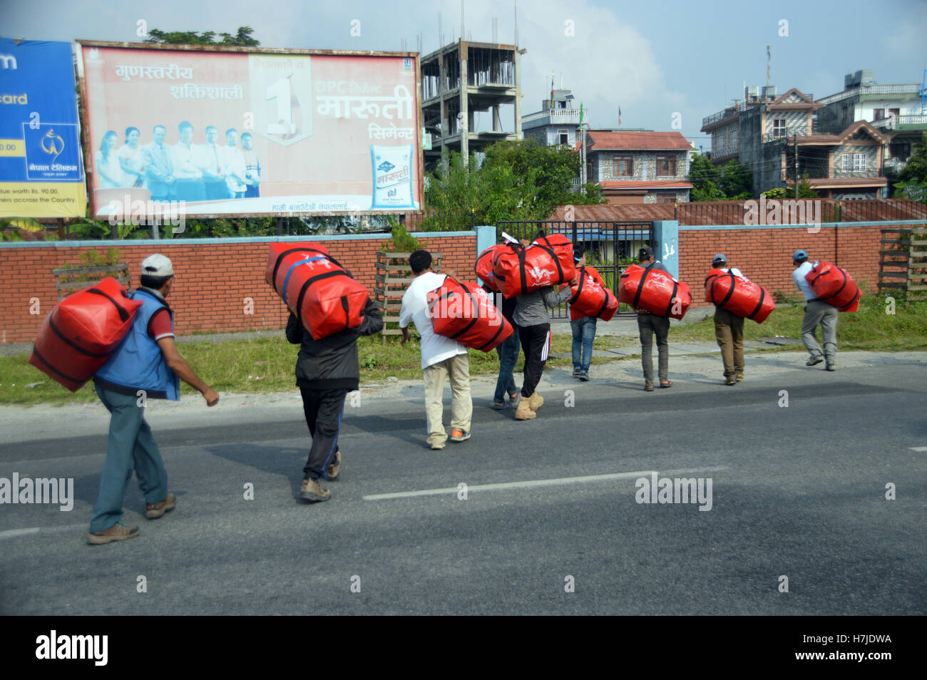 I facchini che trasportano i vacanzieri sacchetti attraverso una strada di Pokhara Airport a un bus in attesa, Nepal, Asia. Foto Stock