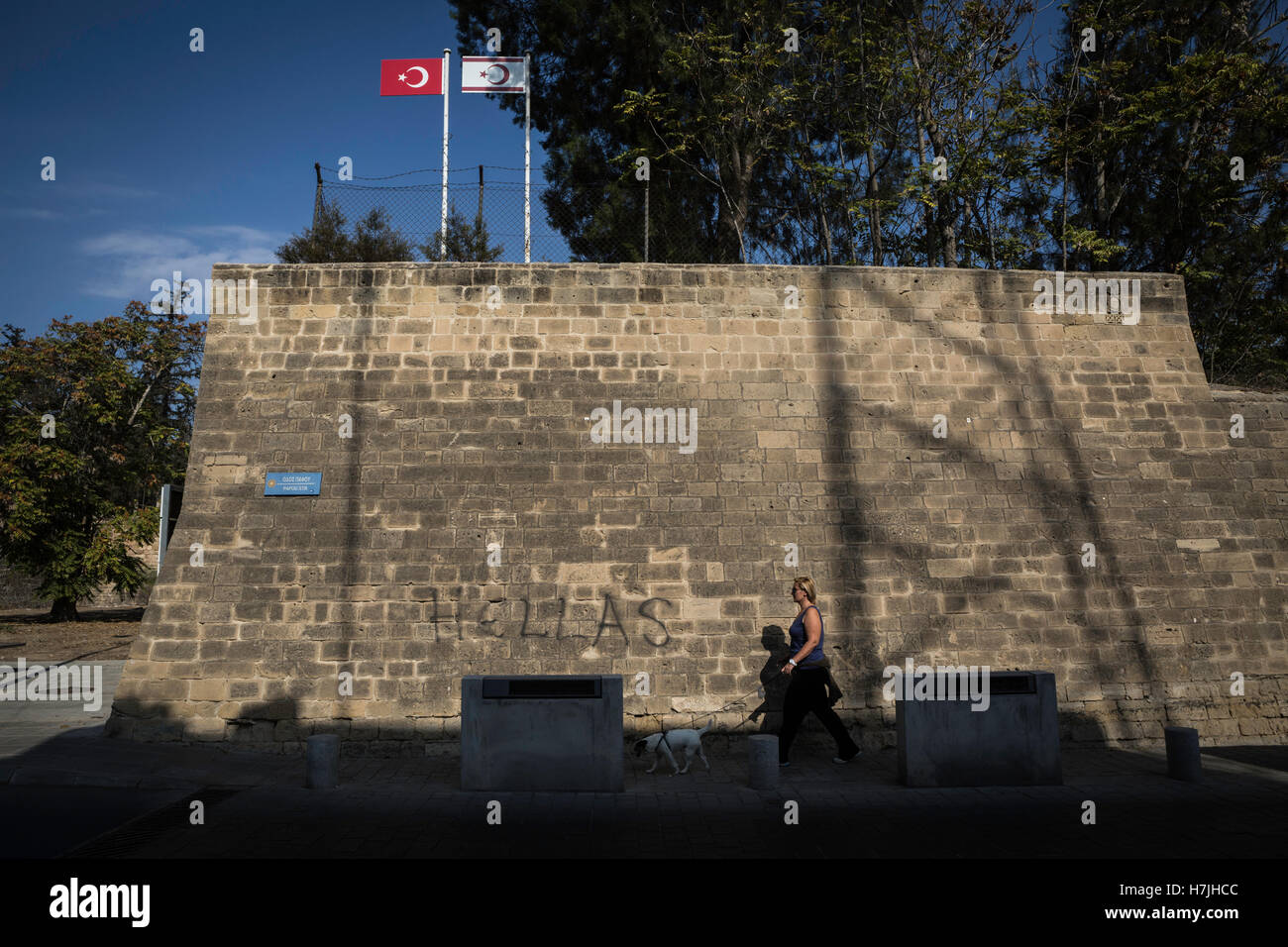 Nicosia, Cipro. 28 ott 2016. Nicosia, l'ultima capitale europea divisa dell'Europa. Una donna cammina con il cane acrossing le mura venete della città. Al di sopra ci sono il turco e la Repubblica turca di Cipro del Nord bandiere. © Sahan Nuhoglu/Pacific Press/Alamy Live News Foto Stock