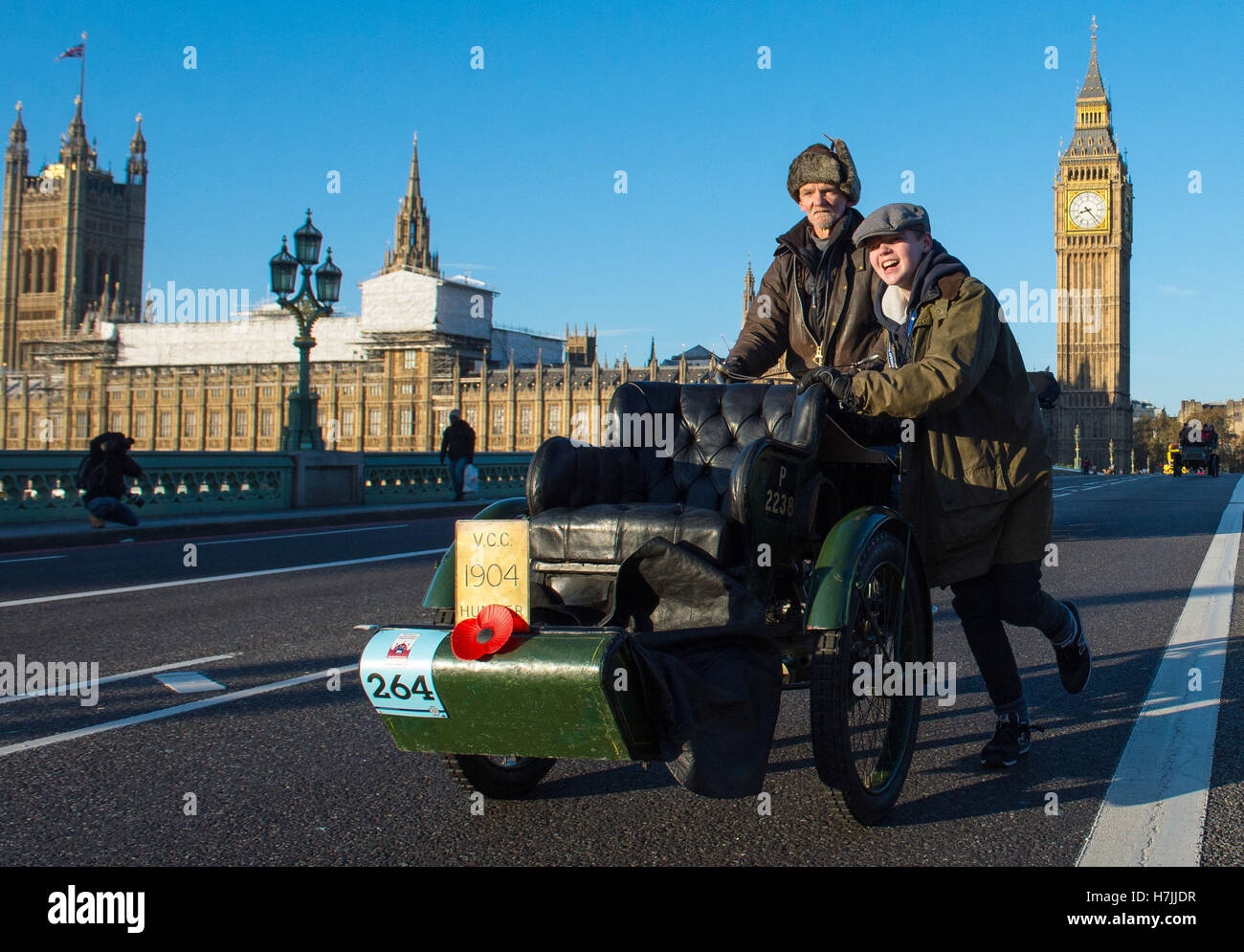 Due partecipanti spingono un'auto Humber del 1904 sopra il Ponte di Westminster durante il Bonhams London alla corsa di auto veterane di Brighton a Londra. Foto Stock