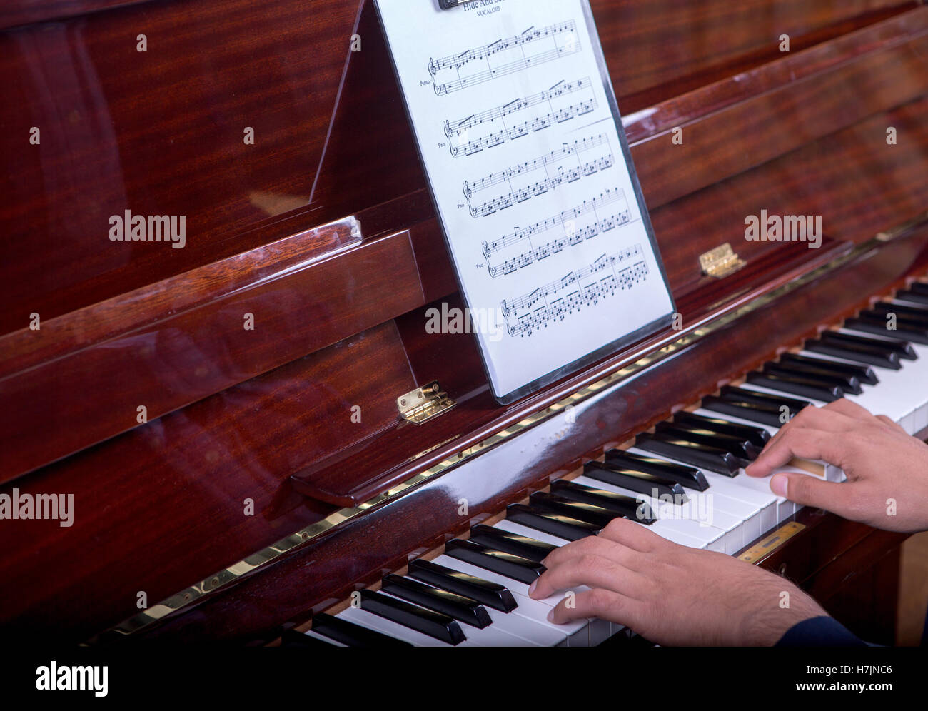 L'uomo suonare il pianoforte mentre è seduto - Vista laterale destra Foto Stock