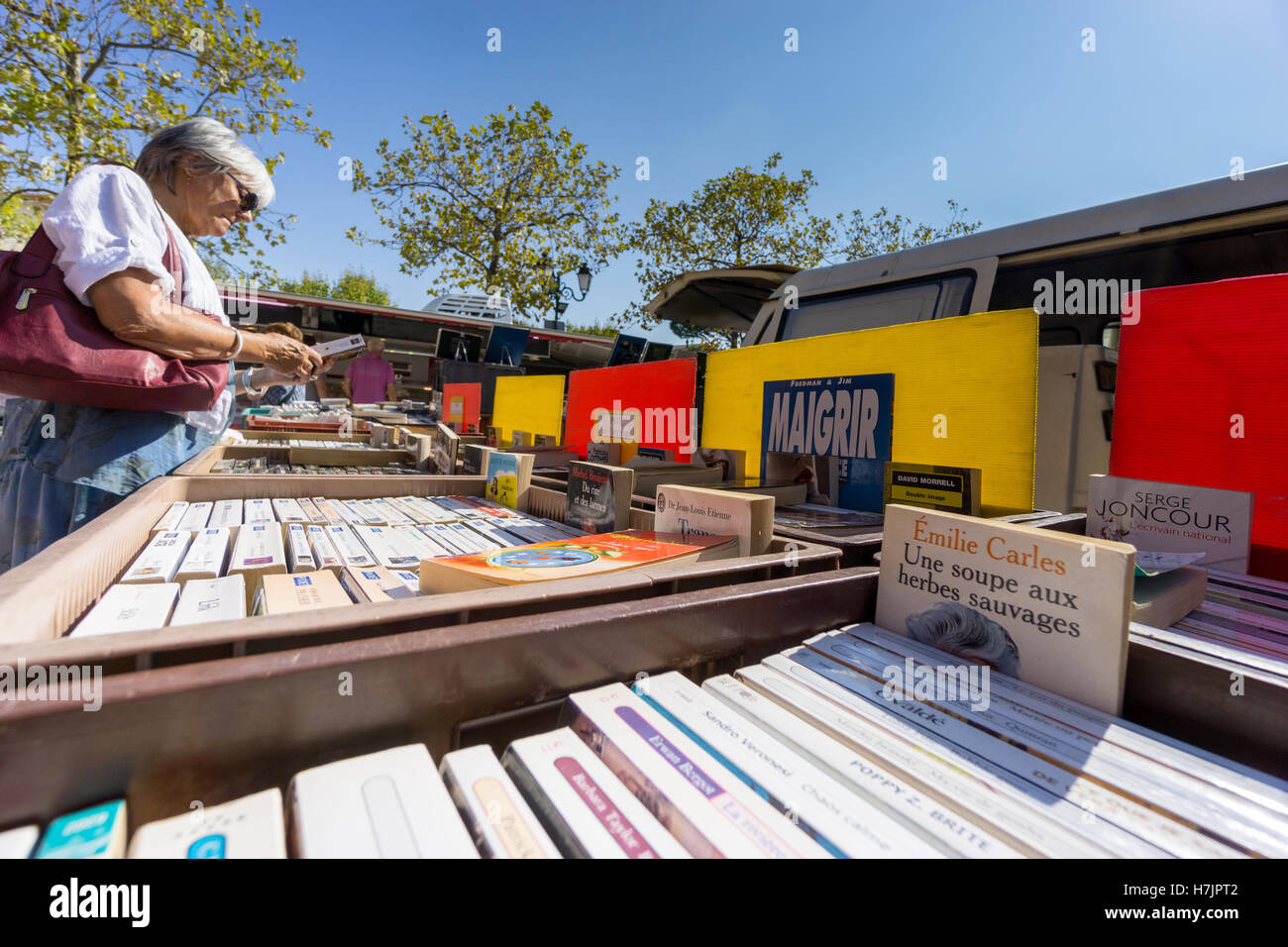 Un cliente femmina peruses un open air di libri usati in stallo Cogolin, Var, Francia. Foto Stock