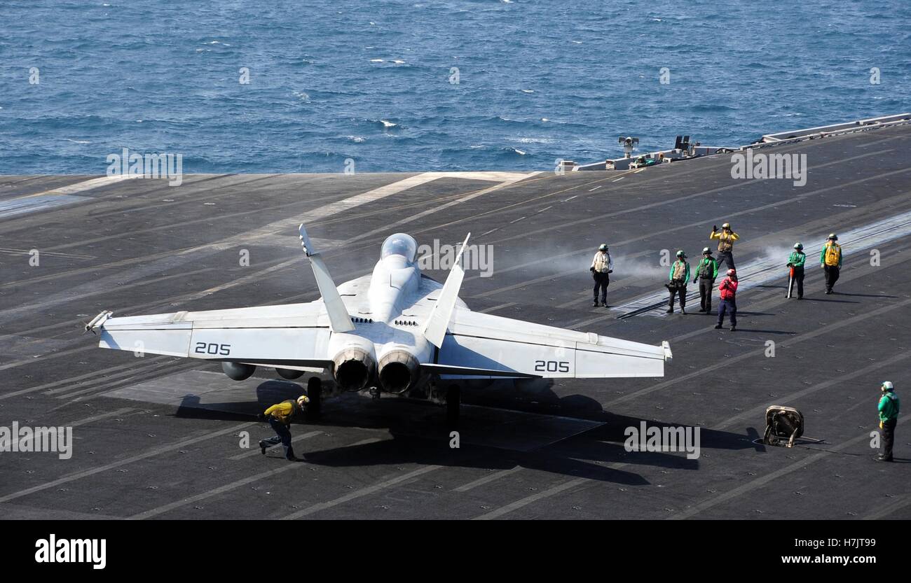 I soldati degli Stati Uniti segnale ad un F/A-18F Super Hornet fighter, aerei di atterraggio a bordo del ponte di volo dell'USN Nimitz-class portaerei USS George H.W. Bussola 13 ottobre 2014 nel Golfo Arabico. Foto Stock