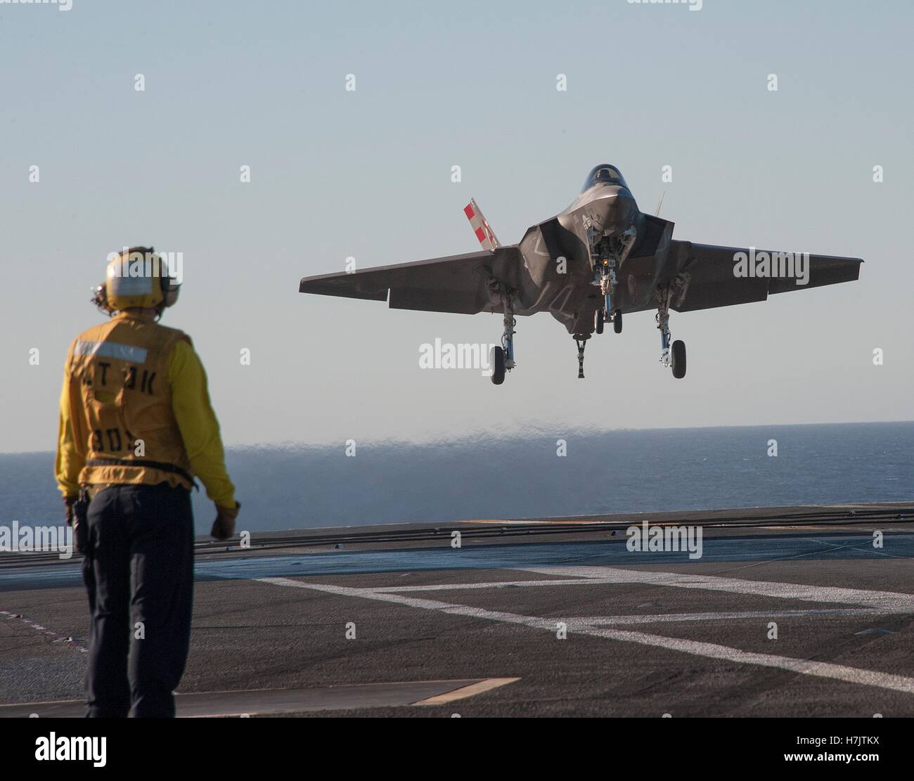 U.S. marinai di standby come un F-35C Lightning II stealth fighter aeromobile atterra a bordo della USN Nimitz-class portaerei USS Nimitz Novembre 6, 2014 nell'Oceano Pacifico. Foto Stock