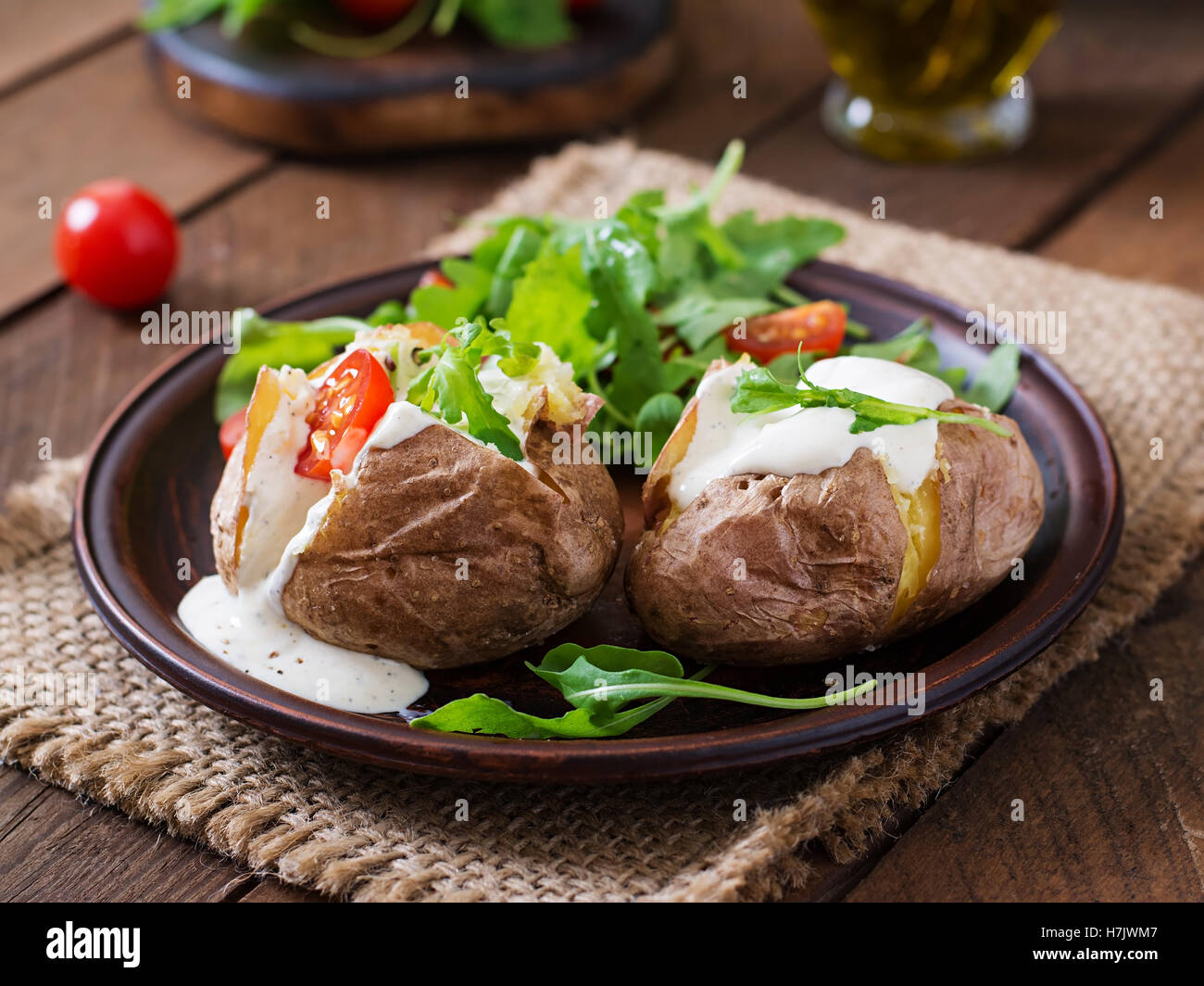Patate al forno riempito con panna acida, rucola e pomodori Foto Stock