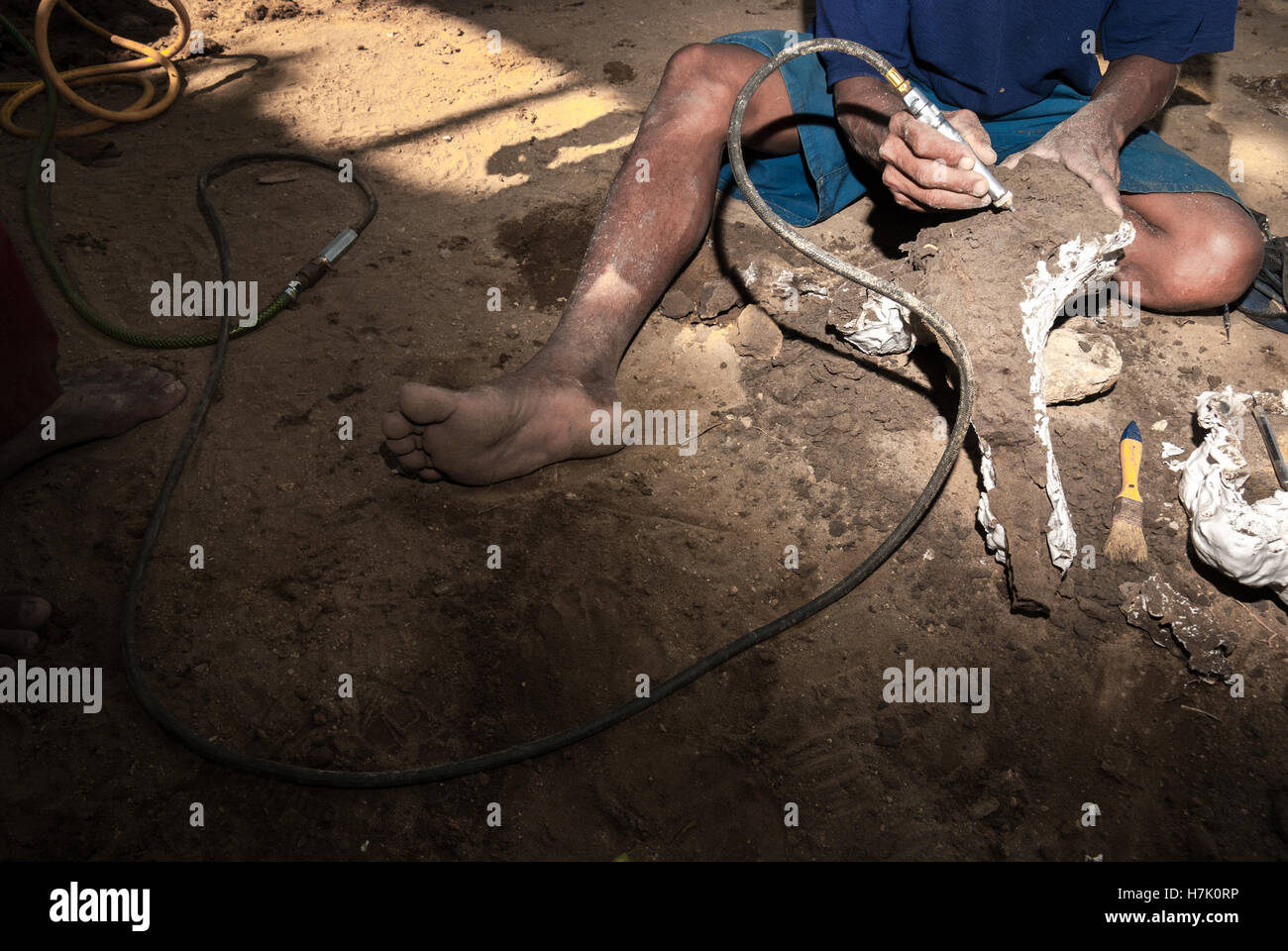 Un villager usa un pulitore mentre sta lavorando con un osso fossilizzato di Elephas hysudrindus, un elefante estinto, a Blora, Giava Centrale, Indonesia. Foto Stock