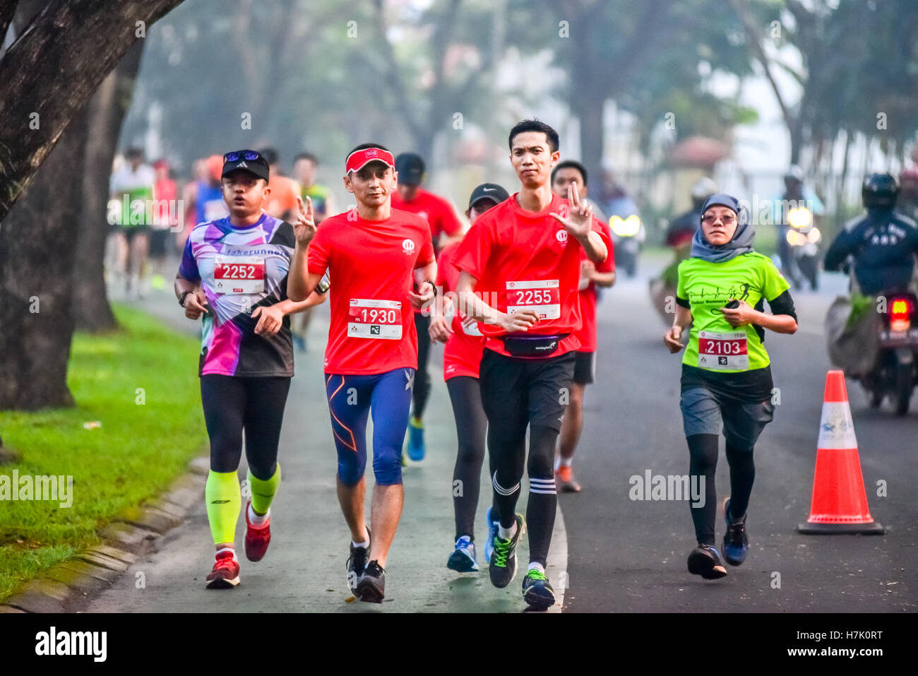 I partecipanti corrono su una strada, passando sotto grandi alberi durante la corsa del Titan 2016 a Tangerang Sud, Banten, Indonesia. Foto Stock