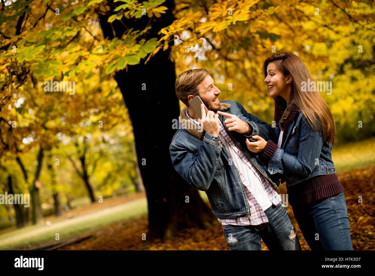 Amorevole coppia giovane in autunno park e uomo che parla al telefono Foto Stock