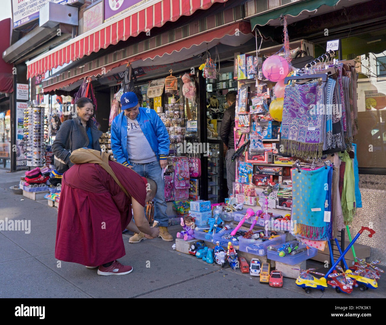 Un monaco tibetano tenuto cellulare foto di canti di vento fino doll su 37th Ave a Jackson Heights, Queens, a New York City, Foto Stock