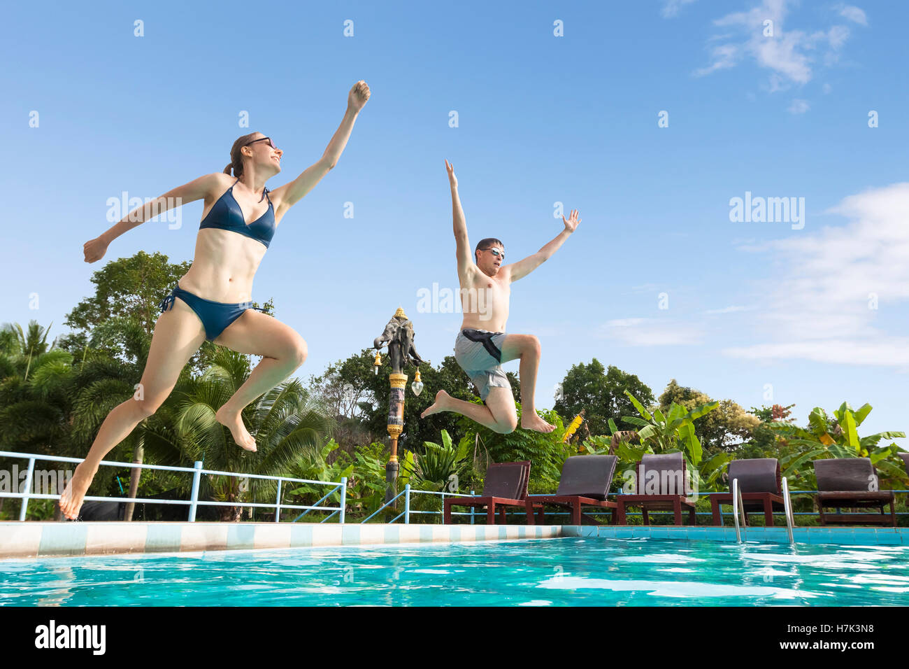 Due amici godere il salto in piscina presso un hotel tropical resort - Concetto di felice divertente vacanza estiva Foto Stock