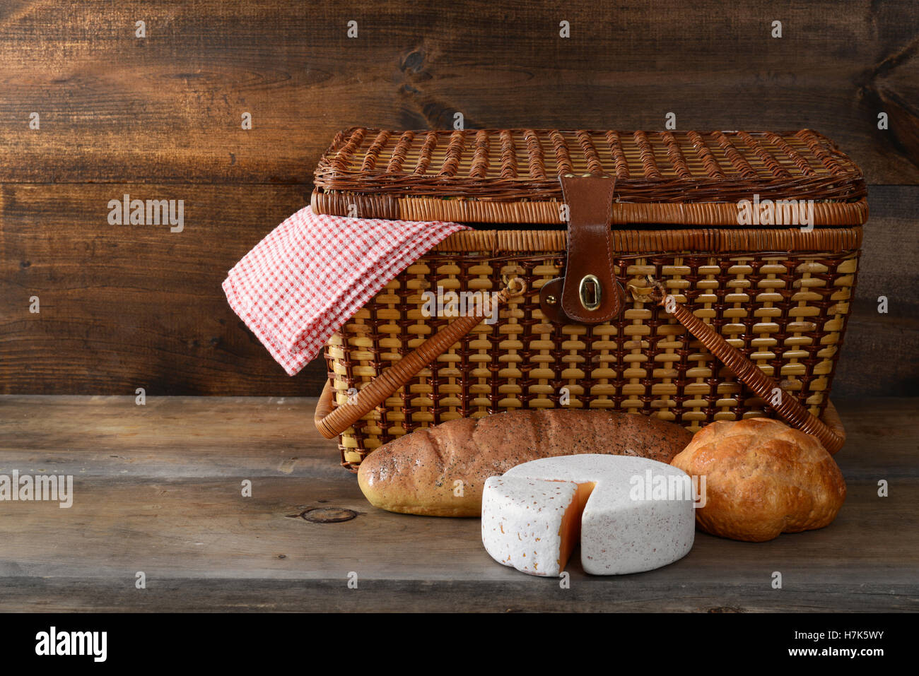 Cesto picnic con pane e formaggio su legno Foto Stock