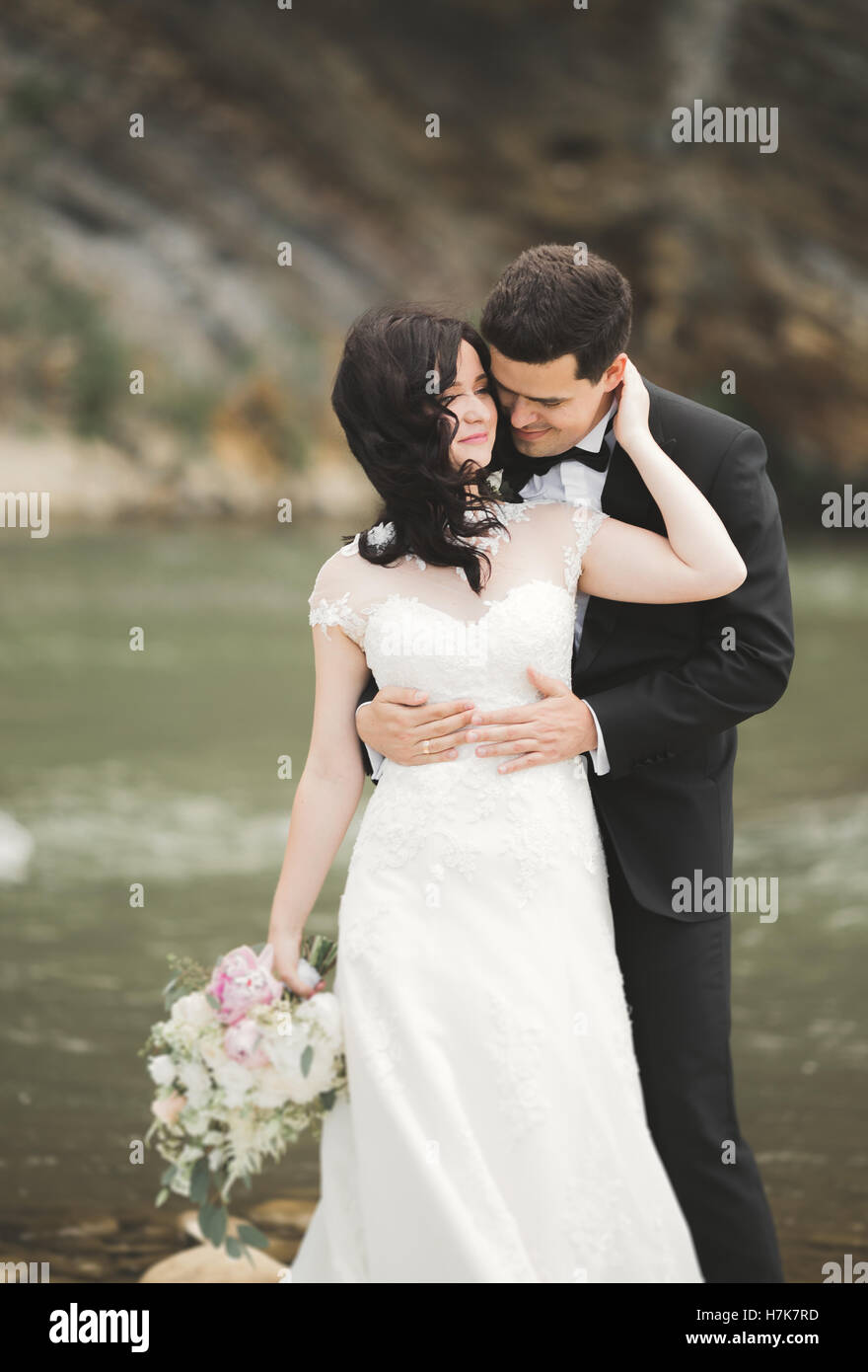 Elegante Elegante dolce per lo sposo e la sposa vicino al fiume con le pietre. Coppie in viaggio di nozze in amore Foto Stock