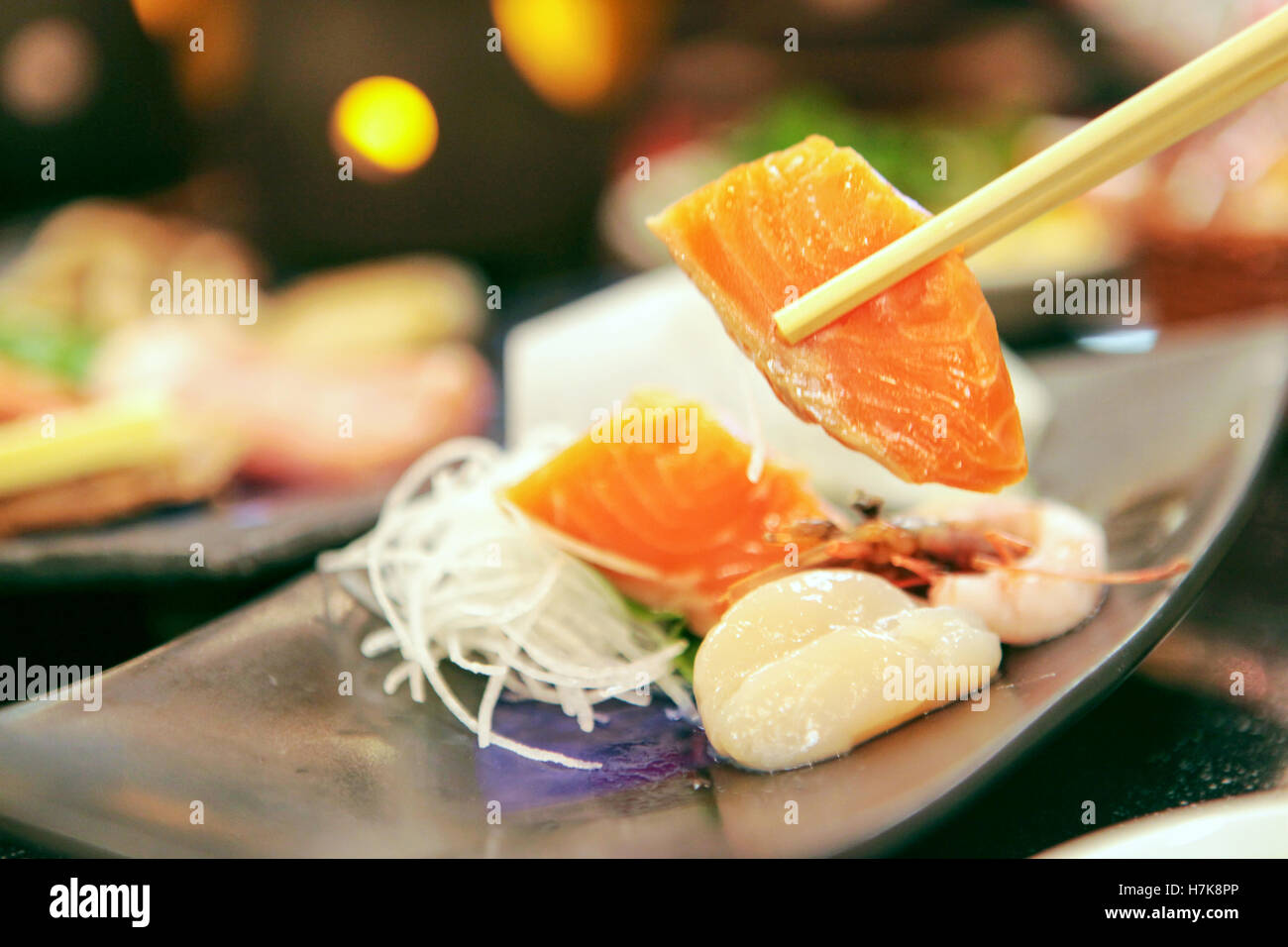 Sashimi di salmone detenute da bacchette Foto Stock