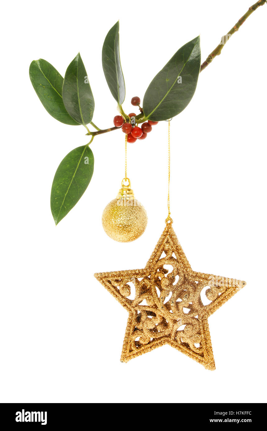 Natale glitter gold star e pallina pendente da un Holly fronda isolata contro bianco Foto Stock