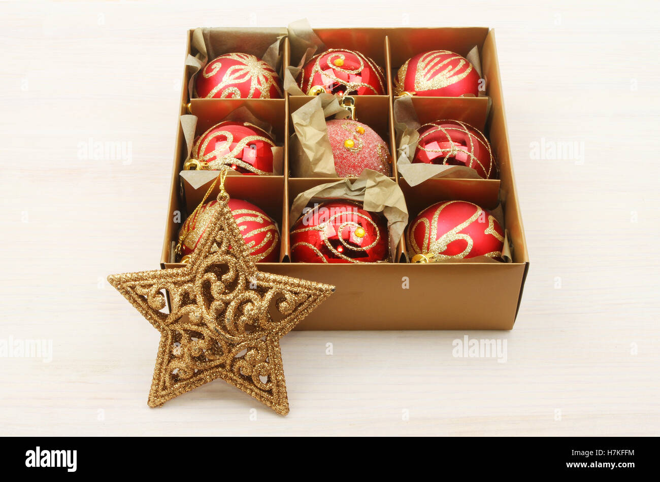 Decorazioni di Natale, baubles in una casella e un oro glitter star su bianco legno verniciato Foto Stock